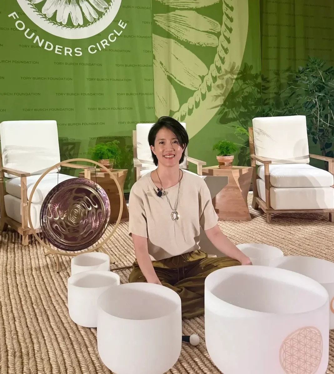Natalie Chan, founder of Soundawn, seated with crystal singing bowls and a gong at a Tory Burch Foundation sound bath event in NYC
