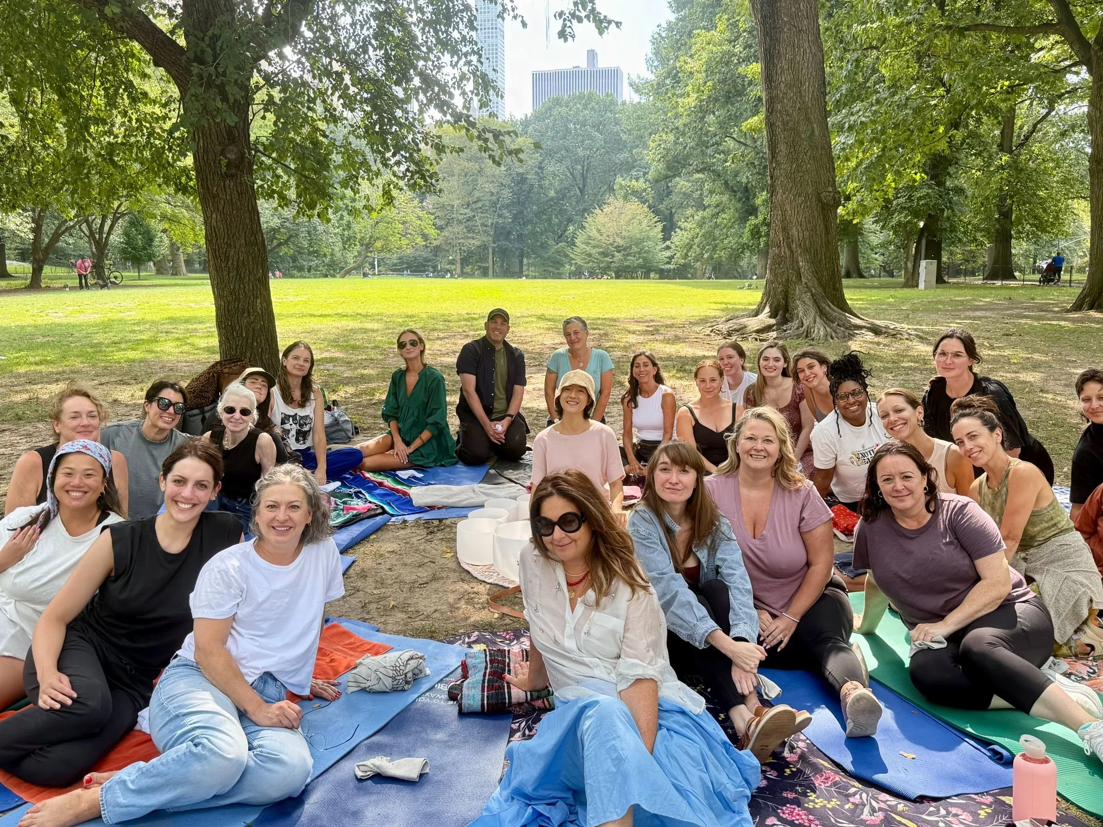 Outdoor sound bath and meditation session in Central Park NYC with crystal singing bowls, creating a calming wellness experience for a group.