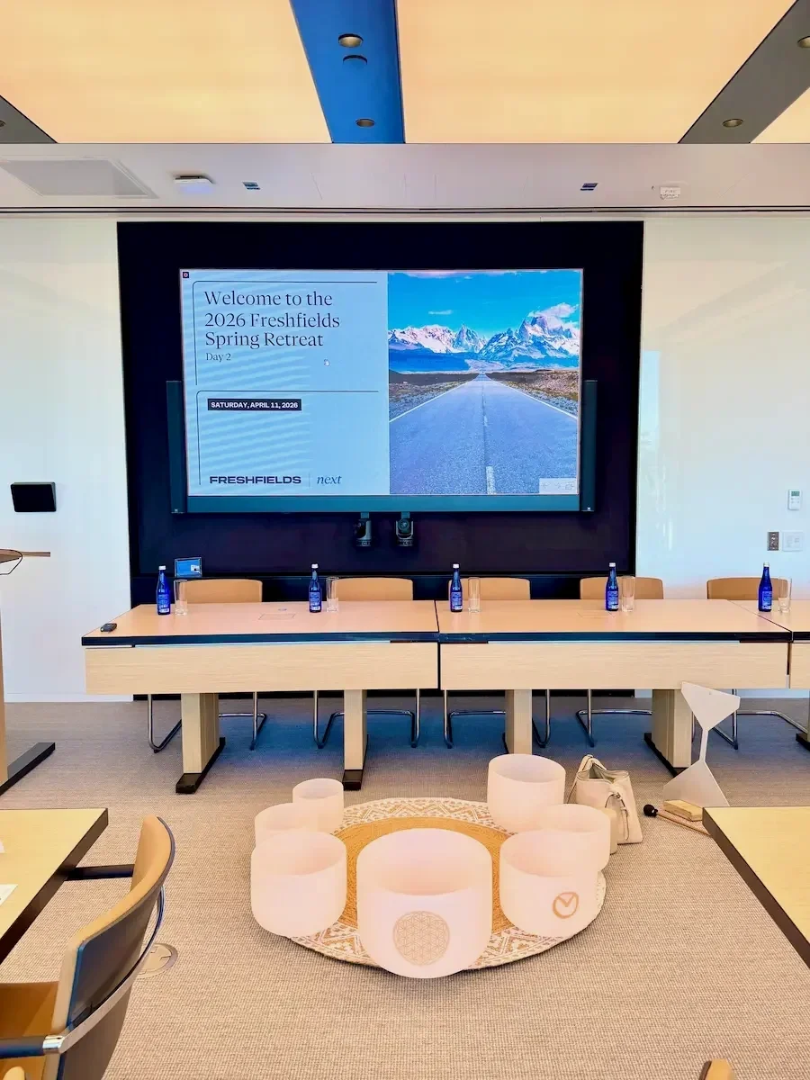 Crystal singing bowls arranged on the floor of a corporate boardroom set for a small-group Soundawn sound bath in NYC.