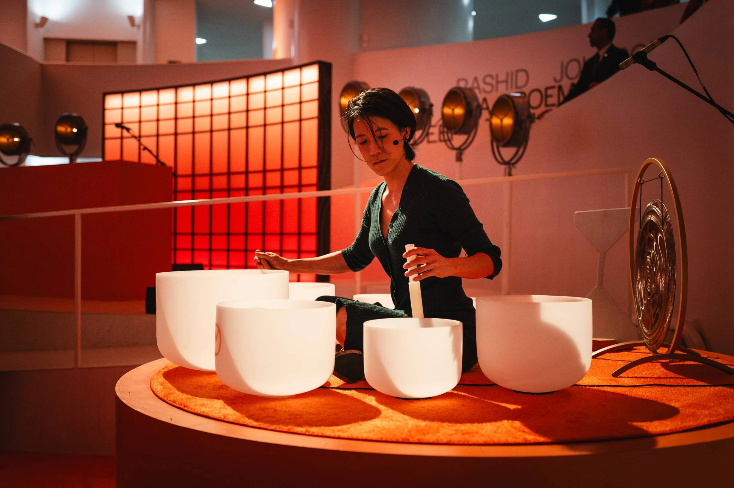 Natalie Chan, founder of Soundawn, performing a sound bath with crystal bowls under warm light at the Guggenheim Museum, embodying calm and presence through sound healing.