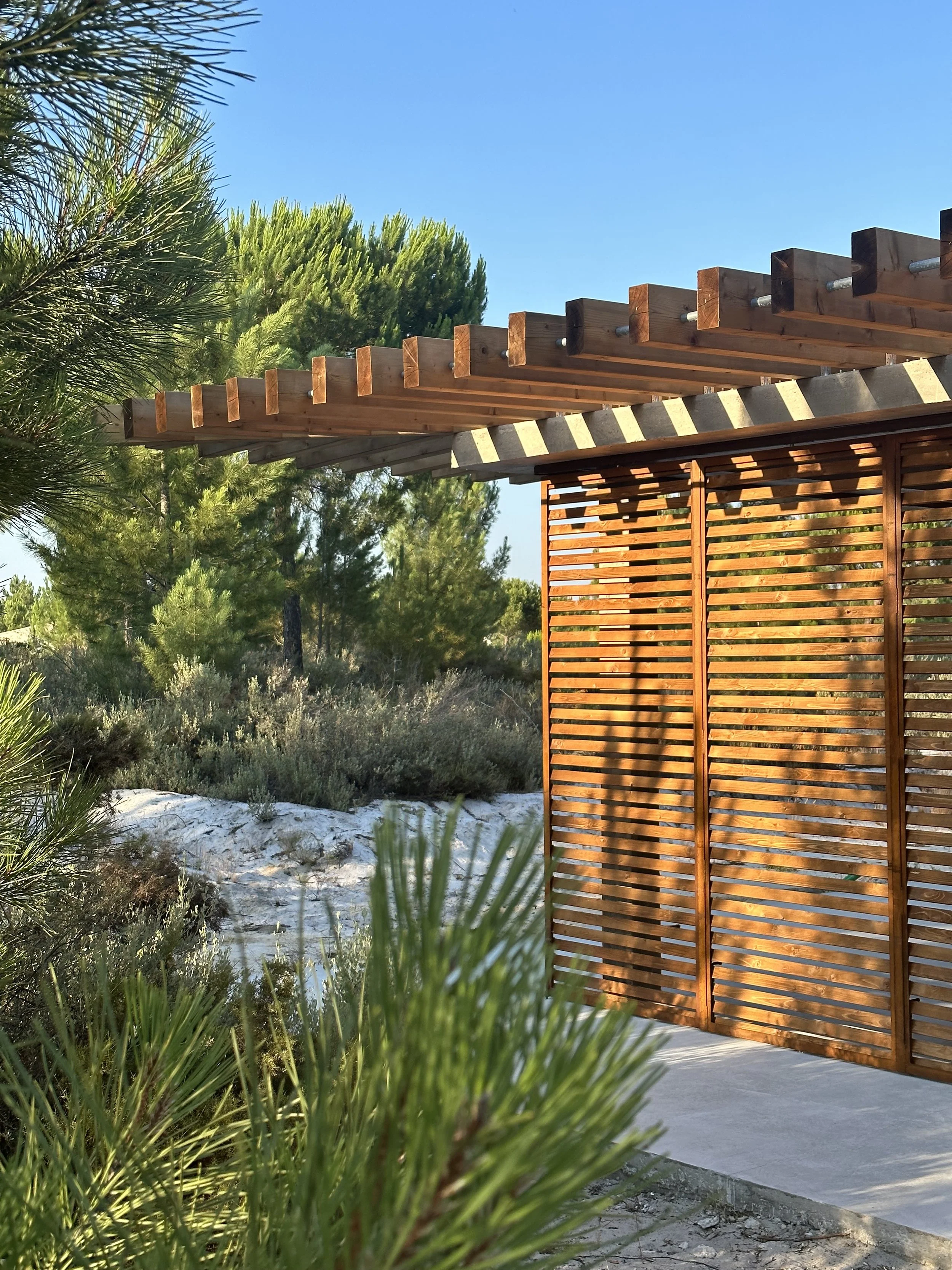 Discover tranquility and wellness at the Yoga Pavilion in Spatia Comporta. This serene space, surrounded by lush pine trees, offers an ideal setting for yoga and meditation practice. Designed with glass walls on all sides and a pitched wooden roof, t