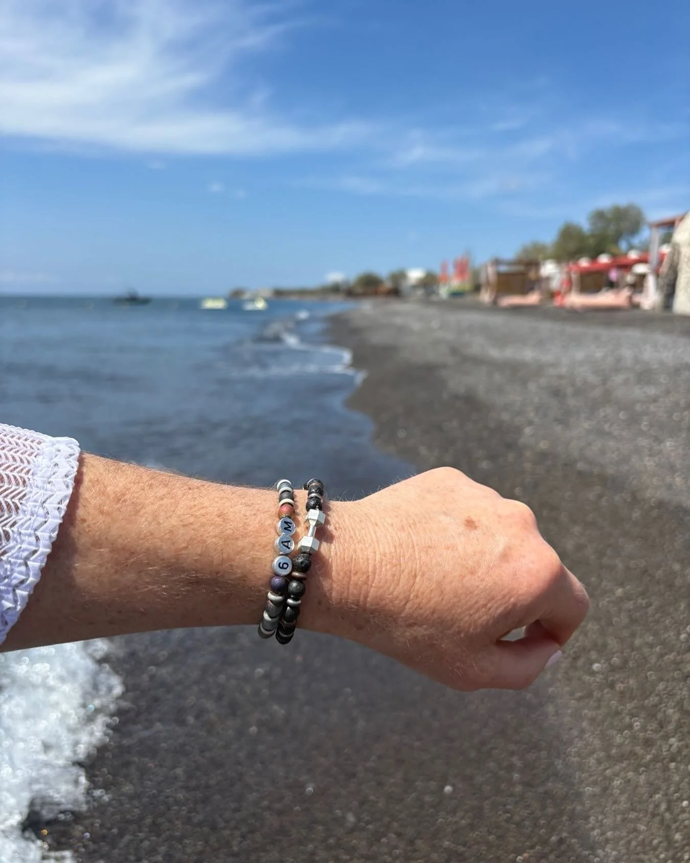 Shamelessly stealing from the sender&rsquo;s text &ldquo;Santorini through the eyes of my 6AM bracelets&rdquo;. We love how you can see the waves coming in and the gorgeous black sand beach. These Zo Much More bracelets are definitely enjoying Greece