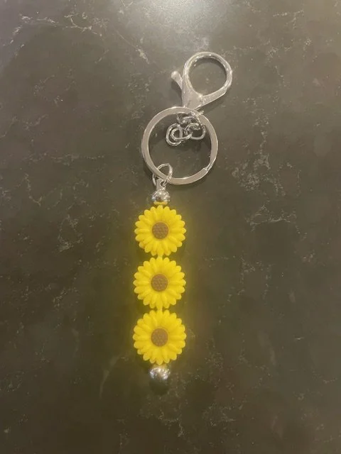 Keychain with yellow sunflower flower charms hanging from a metal ring and clasp.