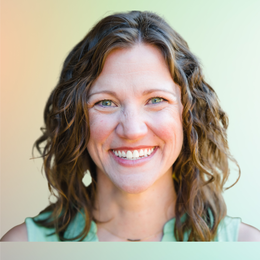 Smiling woman with wavy brown hair and green eyes wearing a mint green top