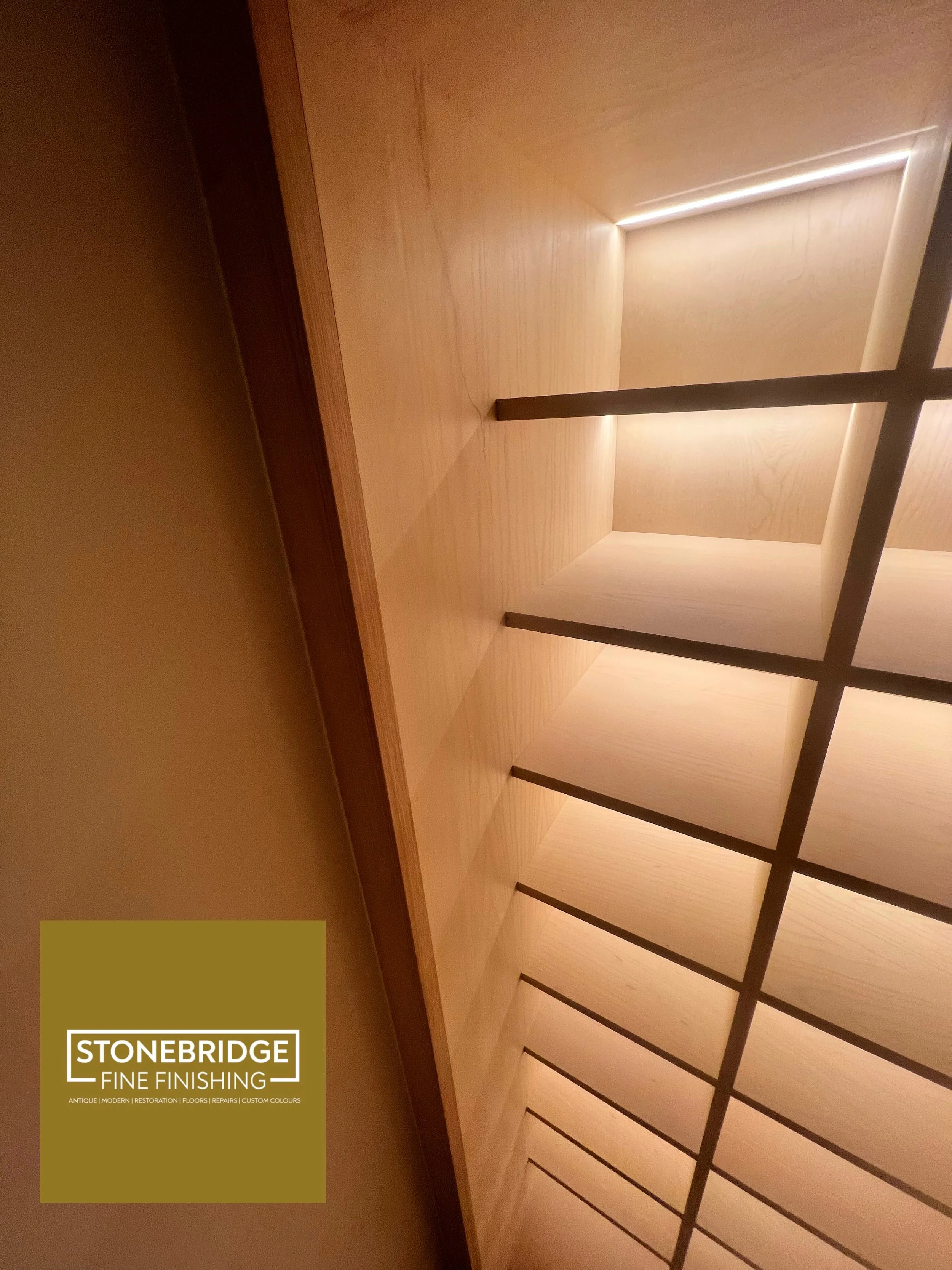Interior view of a room with wooden flooring, walls, and ceiling, featuring a grid ceiling design and subtle lighting along the edges.