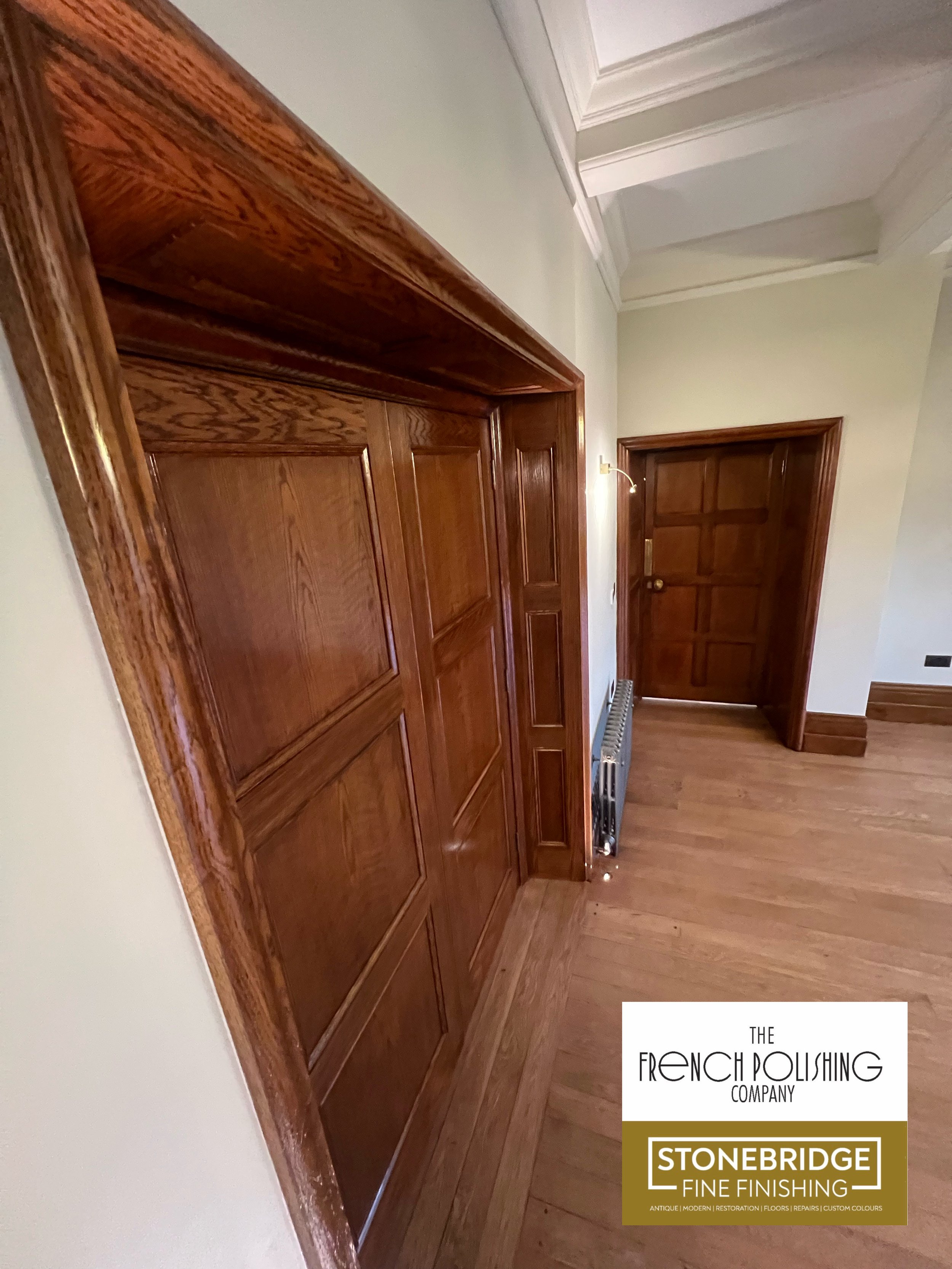 Close-up view of a wooden interior door and surrounding wood trim in a room with light-colored walls and hardwood flooring.