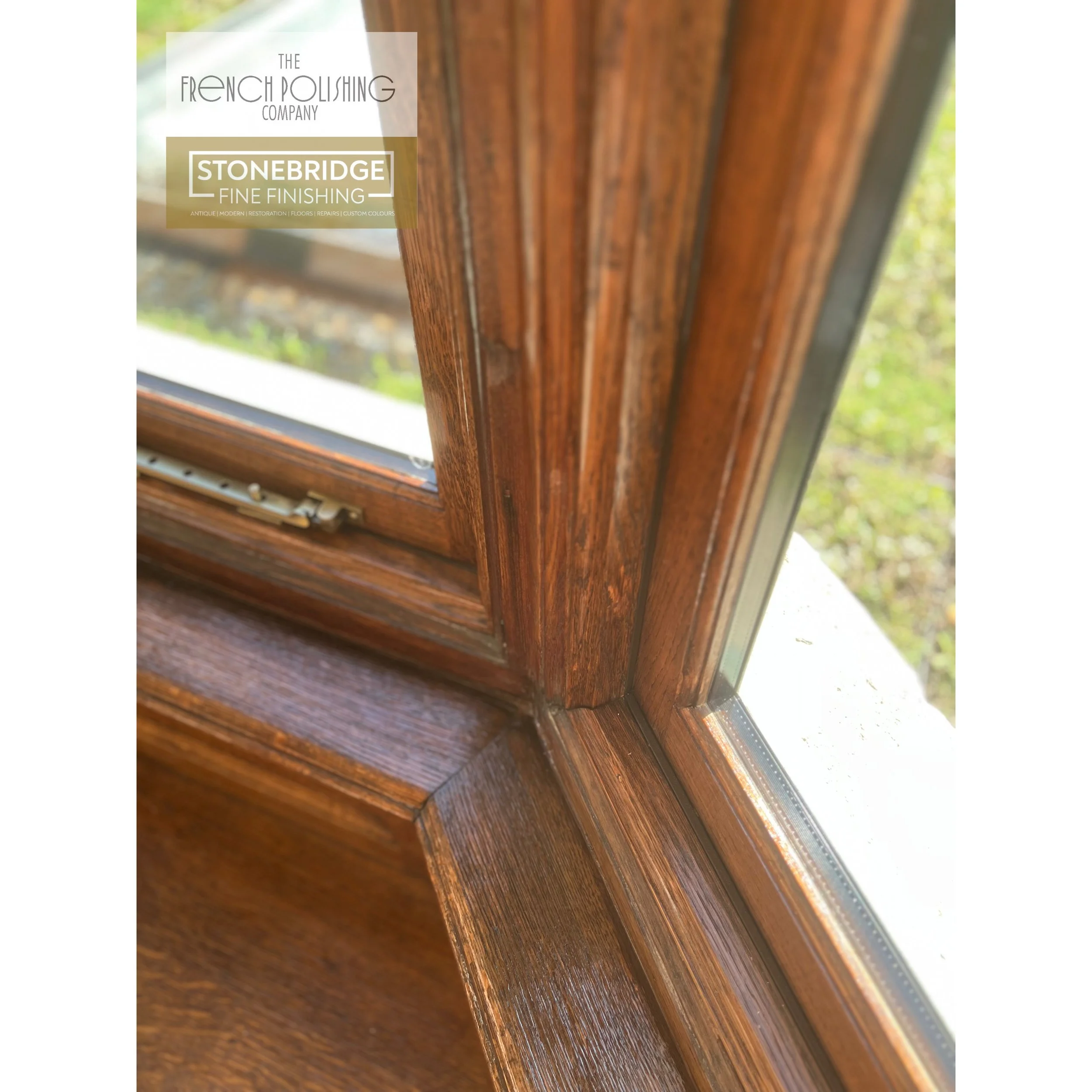 Close-up of a wooden window frame with a view of the outdoors through the glass, showing greenery in the background.
