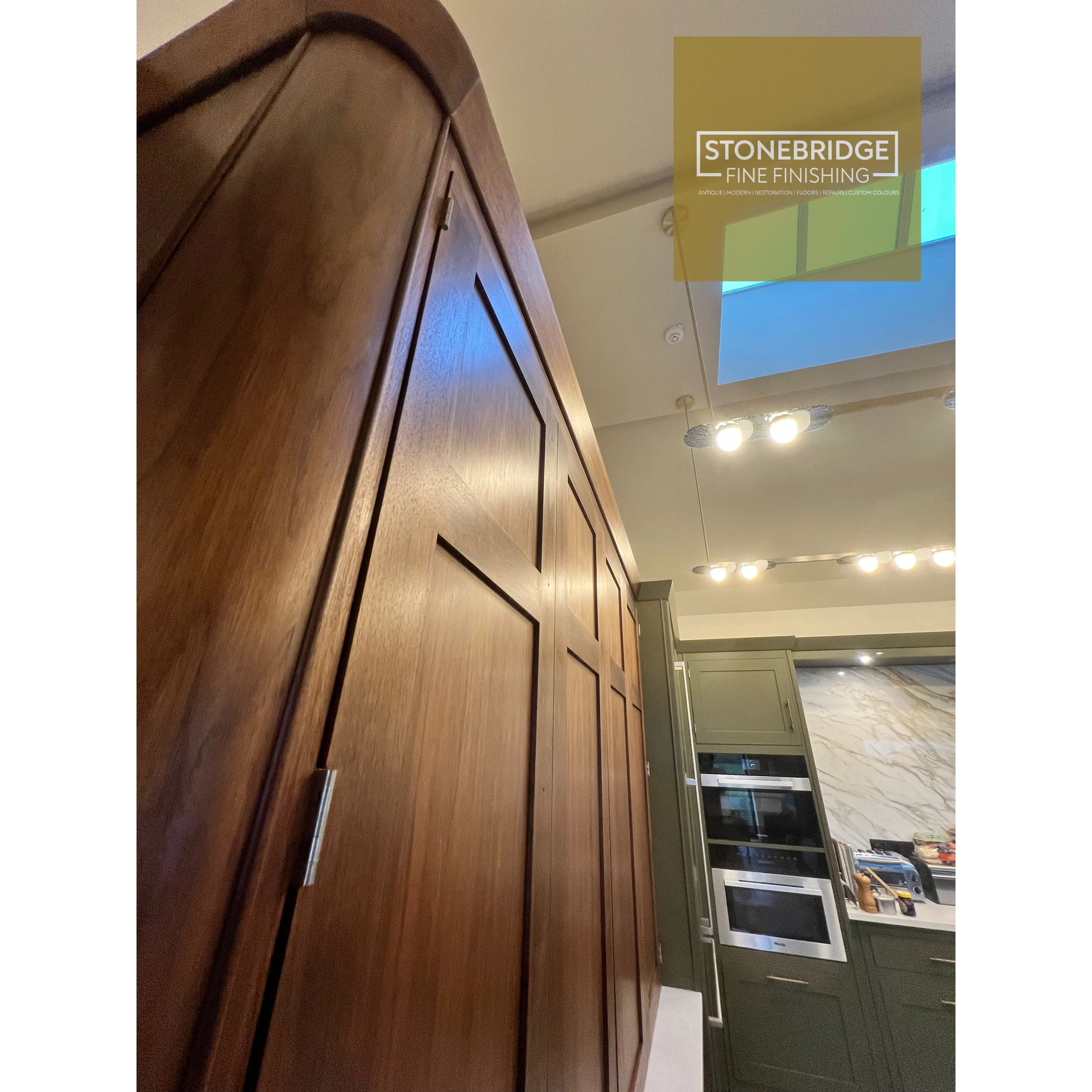 Wooden cabinet with raised rectangular panels, part of a kitchen or living space interior.