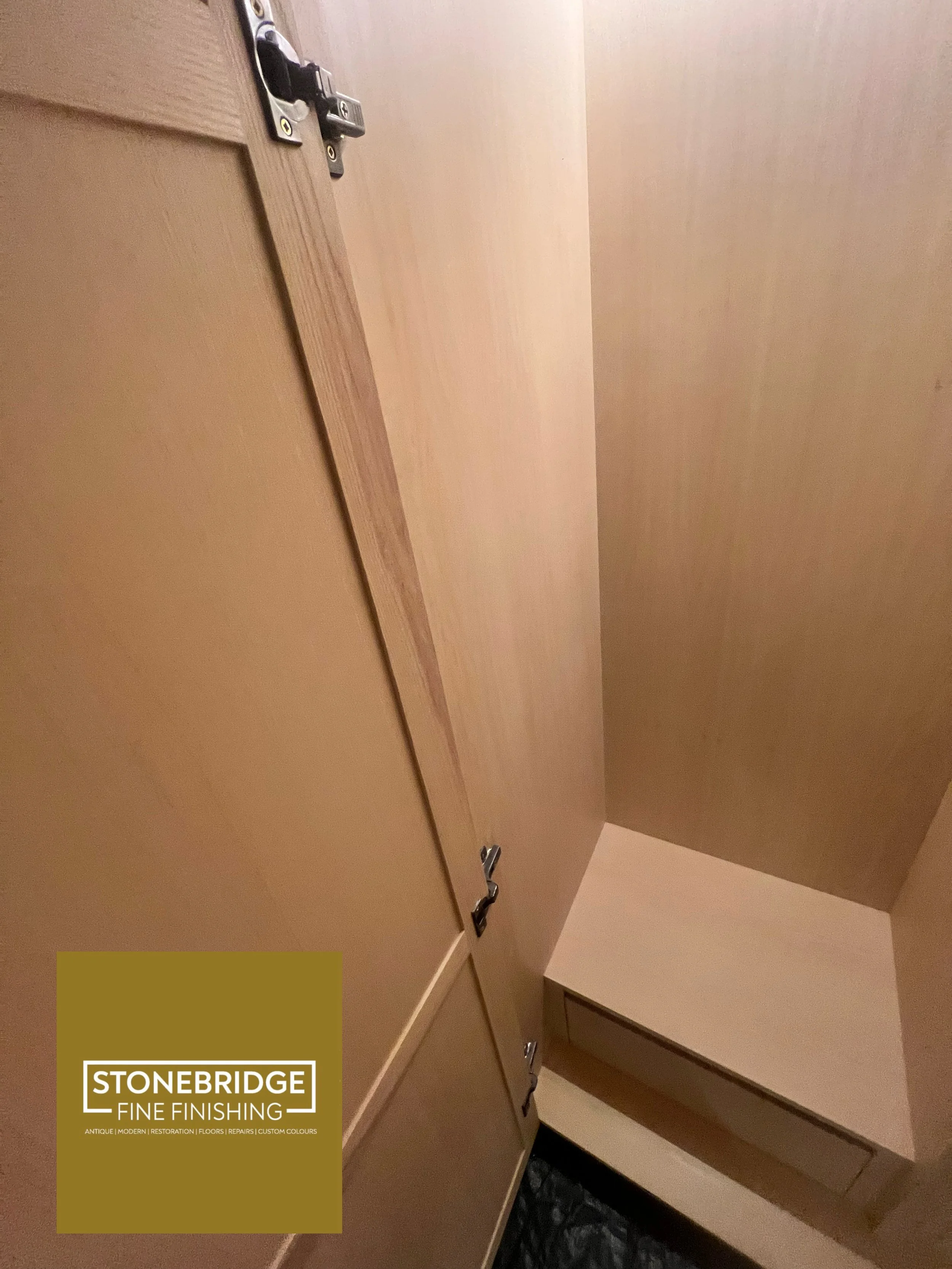 Interior view of a wooden cabinet or closet showing multiple drawers or compartments with metallic handles. There is a logo label in the bottom left corner of the image reading 'Stonebridge Fine Finishing'.