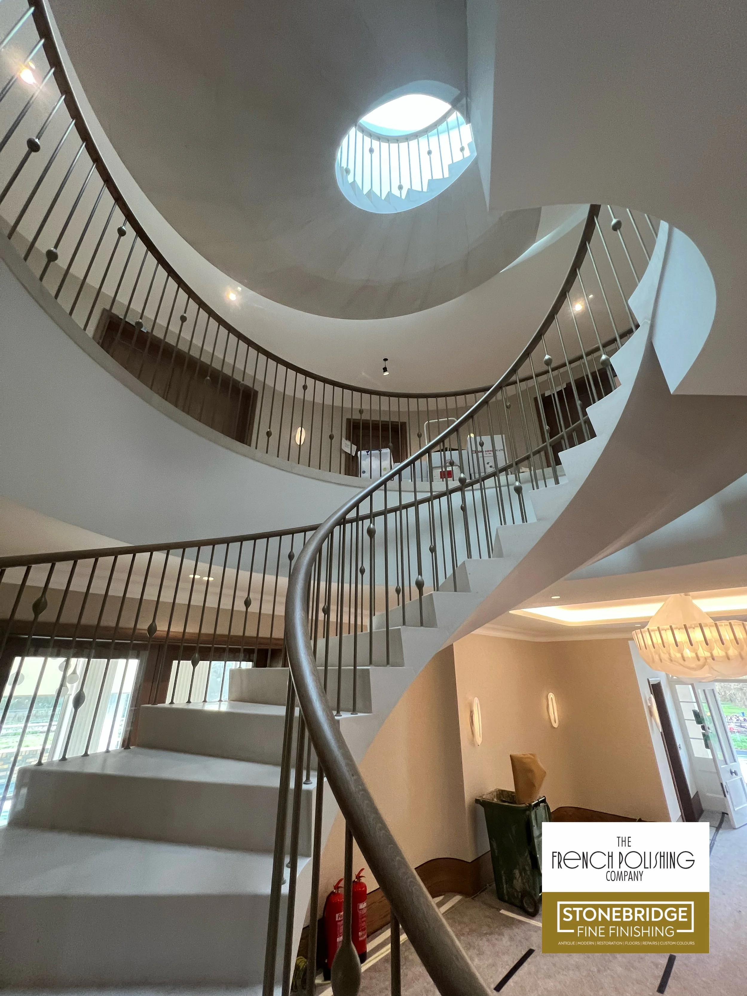 Spiral staircase viewed from below with natural light coming from a skylight above.