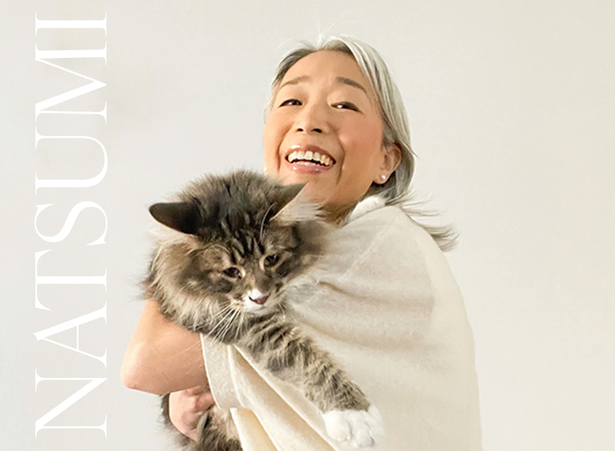 Smiling woman holding a fluffy tabby cat against white background
