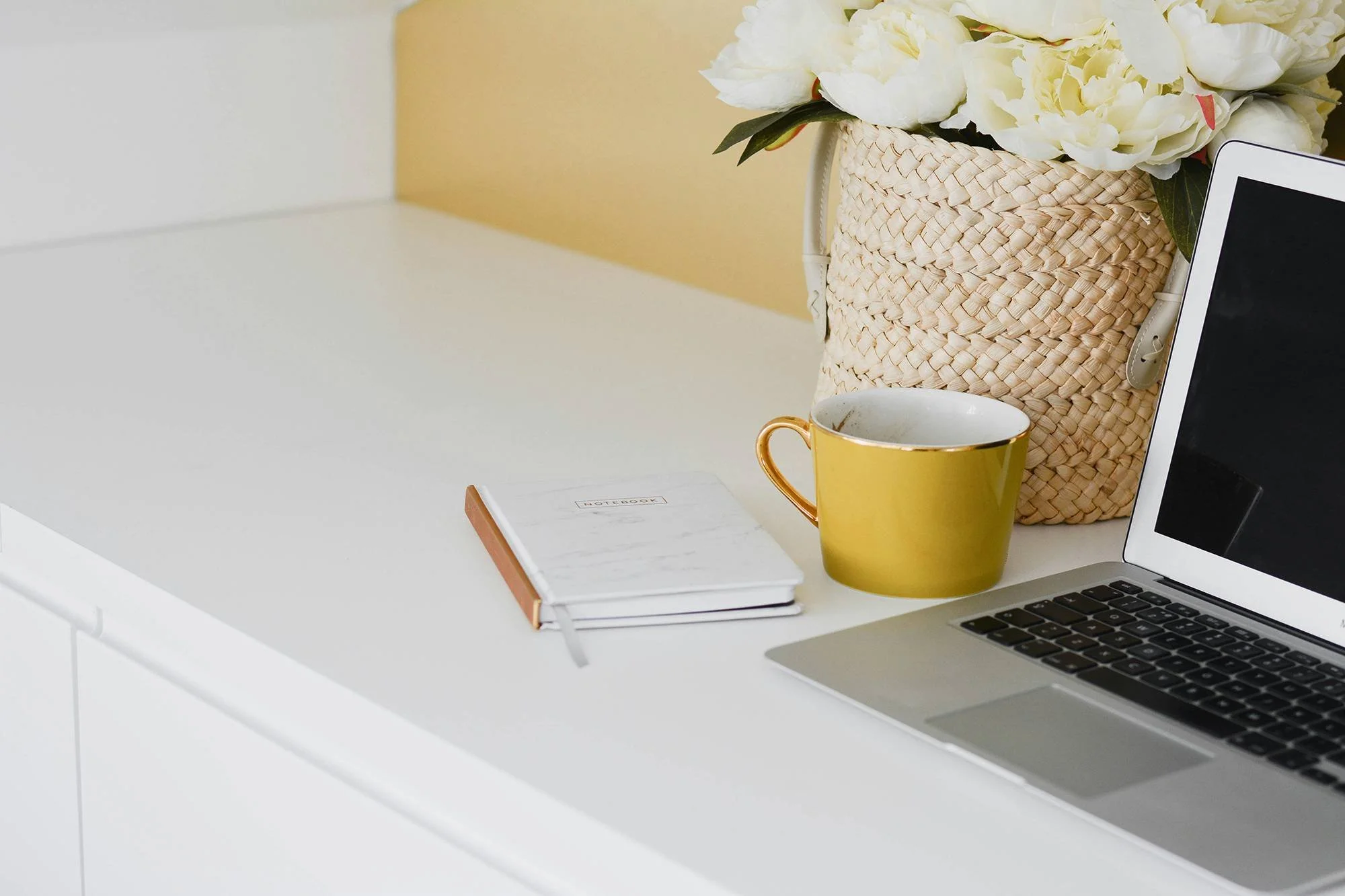 Clean desk with fresh flowers, a laptop, and a notebook in a modern workspace