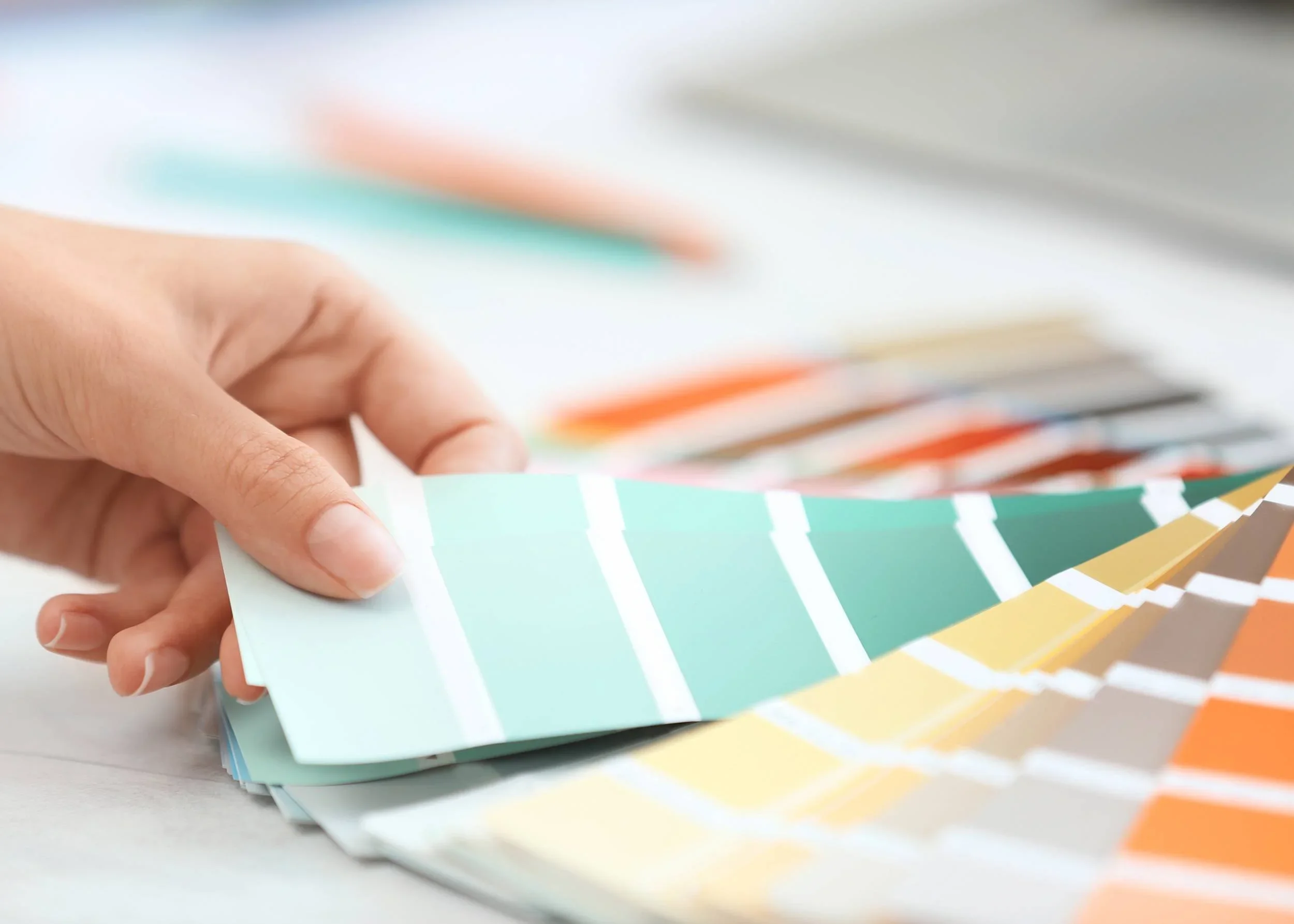 Hand flipping through color swatches in green, yellow, orange, and brown