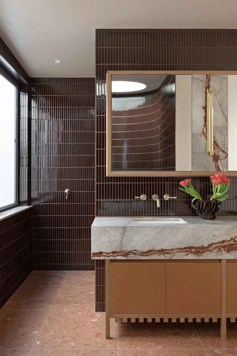Brighton House — Inside, materials are warm and tactile. Terracotta tones, blackbutt timber and rendered surfaces create a grounded interior, while joinery is expressed as furniture.