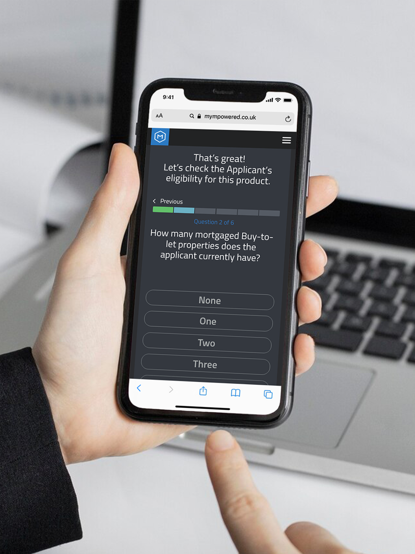 Person using a smartphone to answer a financial eligibility quiz on a website, with a laptop in the background.