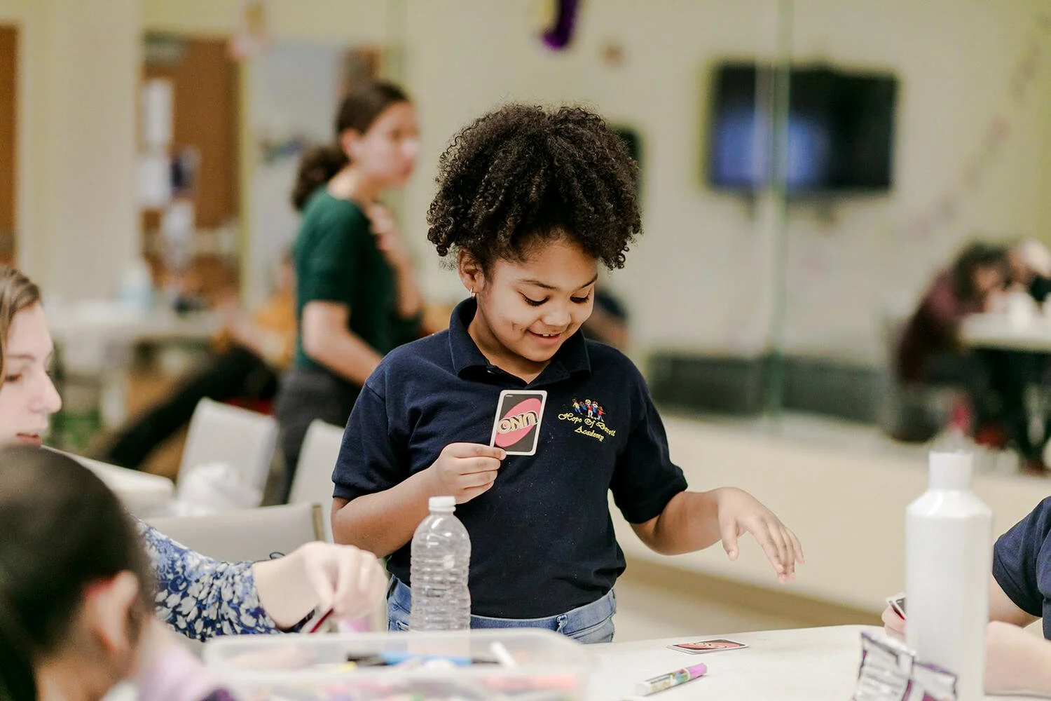 A child playing a card game at a table with others