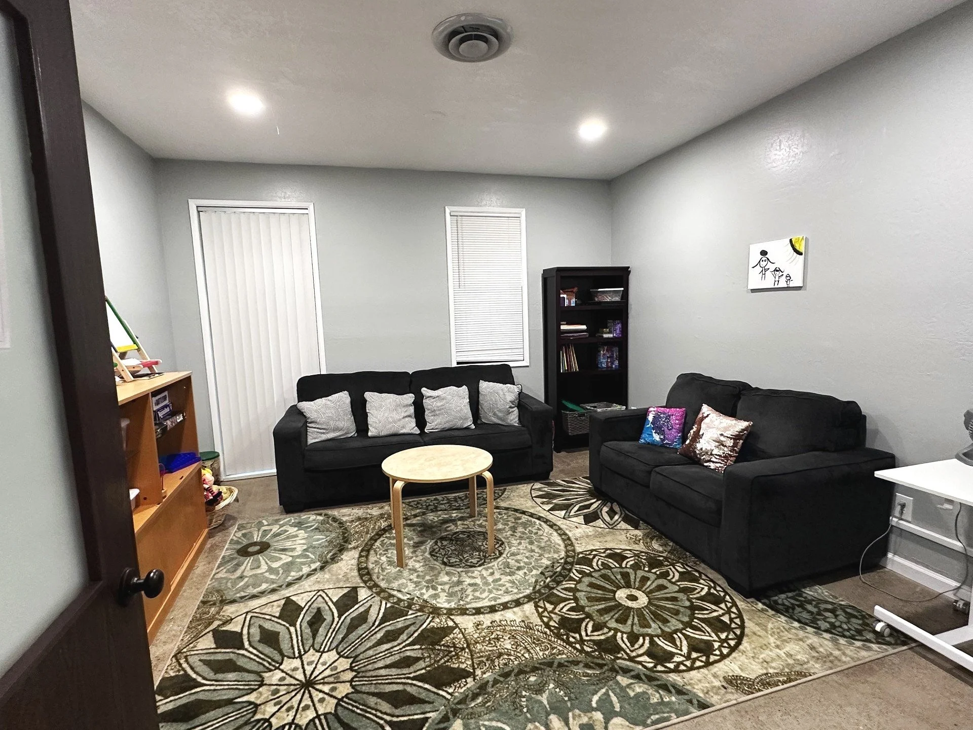 MCYP Supervised Visitation Play Room decorated with children's toys, a couch, a small table, and two stools