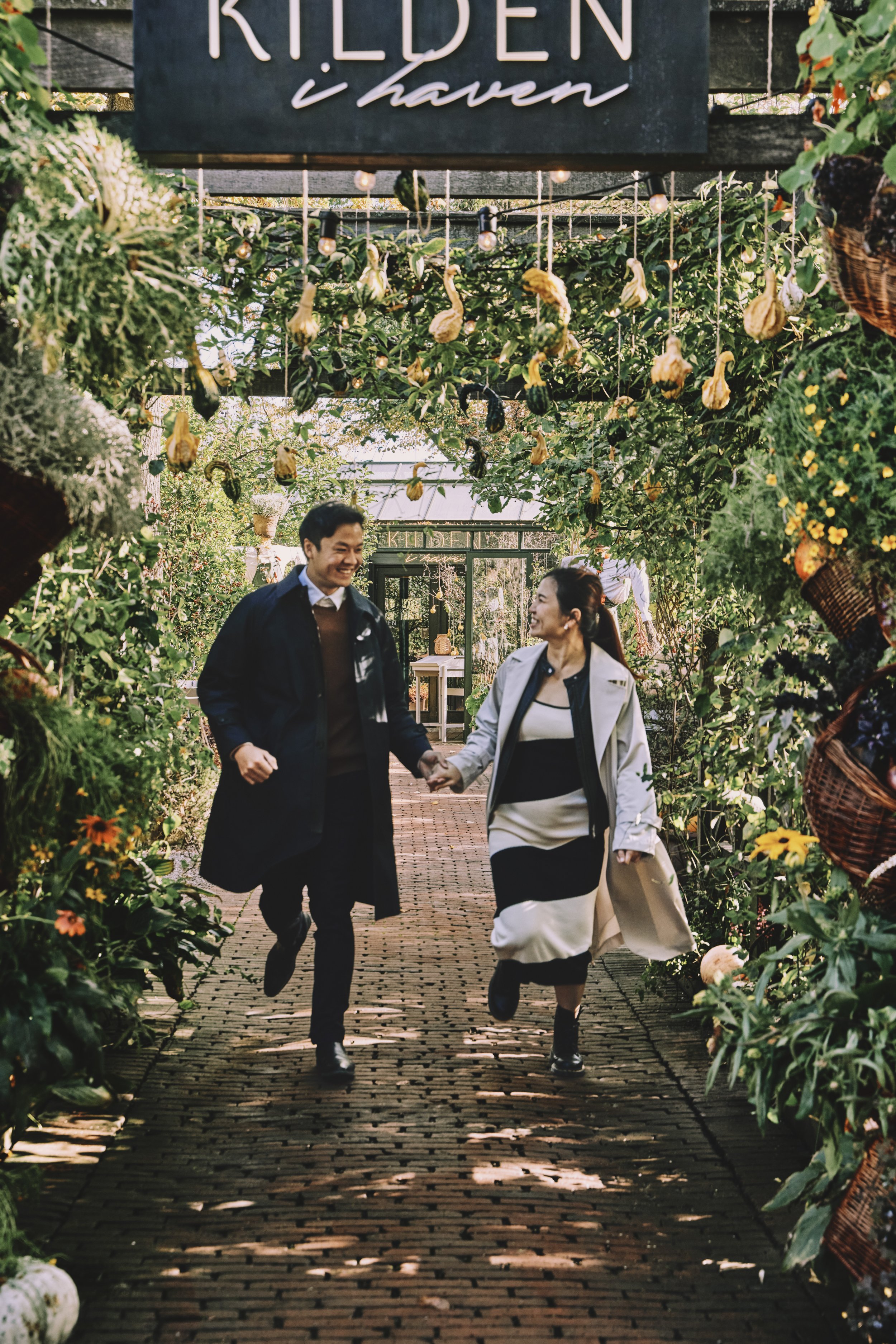 Young woman sitting on grass under cherry blossom trees, looking up thoughtfully.