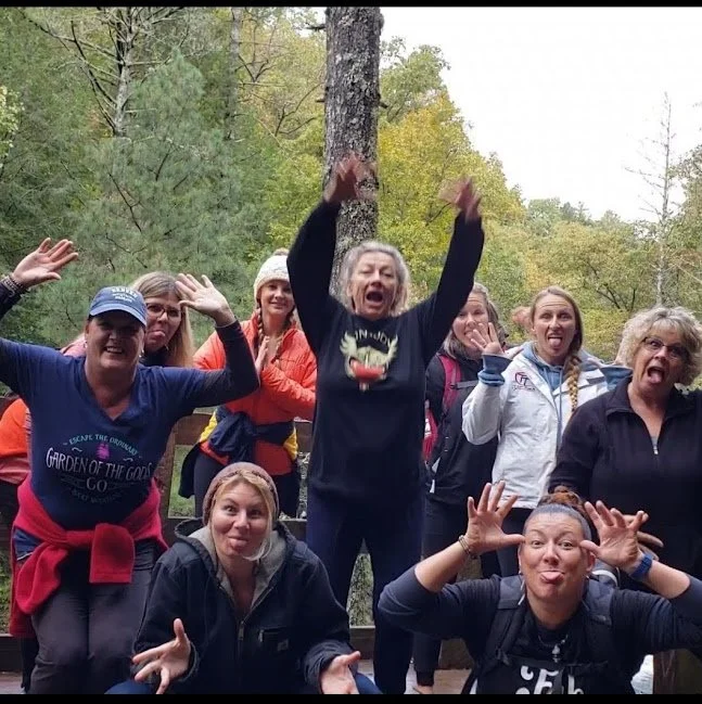 Group of people outdoors in a forest, making funny faces and poses for a photo.