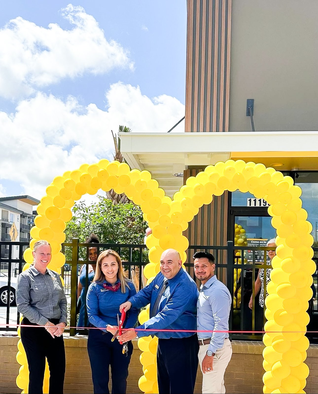 Ribbon cutting at McDonald's with balloon decor. Corporate grand opening for