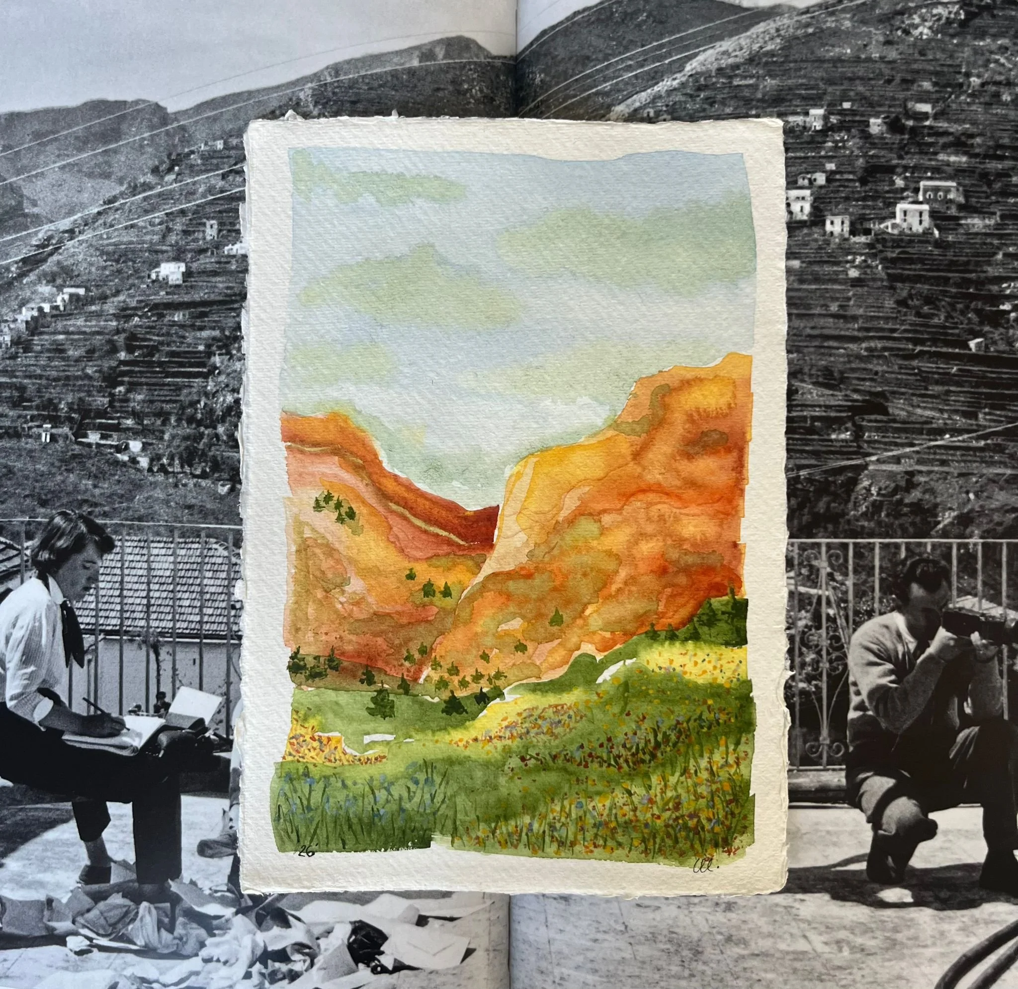 A watercolor painting of a mountainous landscape with a valley, trees, and a sky with clouds, placed over a black-and-white photograph of two people sitting on a bench outdoors.