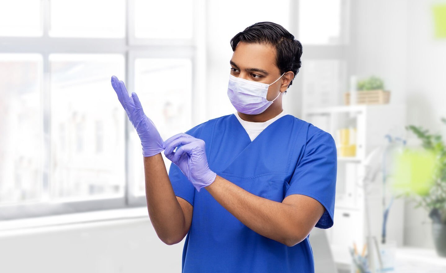 Tandläkare som använder engångshandske i nitril och engångsmunskydd i en violett färg.