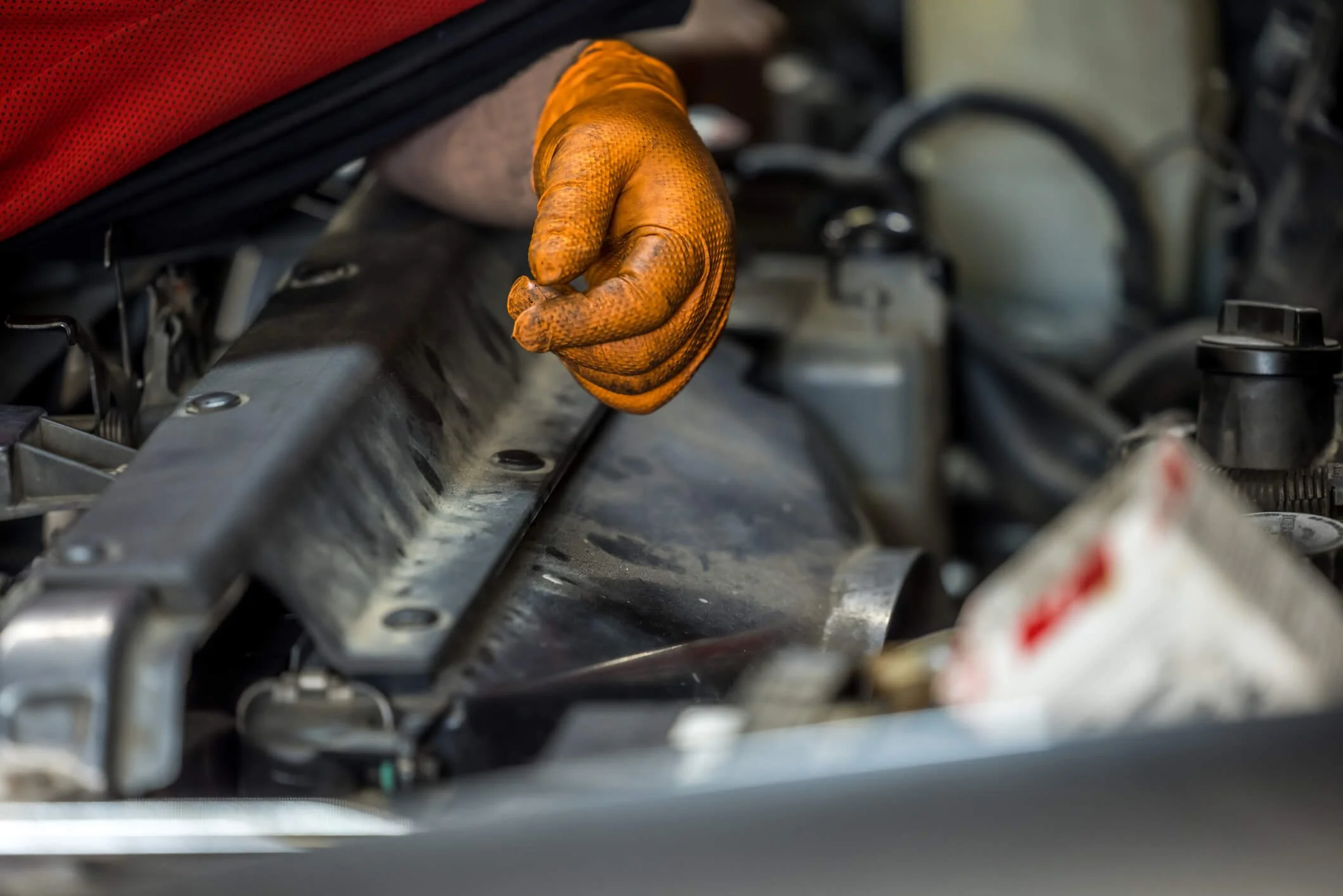 The picture shows a hand wearing nitrile gloves with diamond texture and the background is under a bonnet