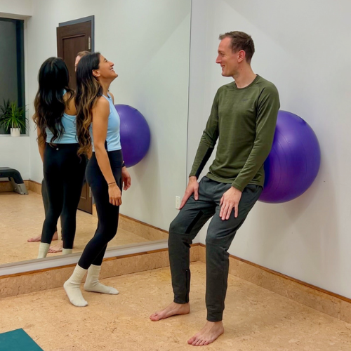Aasia teaching personal fitness  in a small studio, with a stability ball against the wall. Personal training session