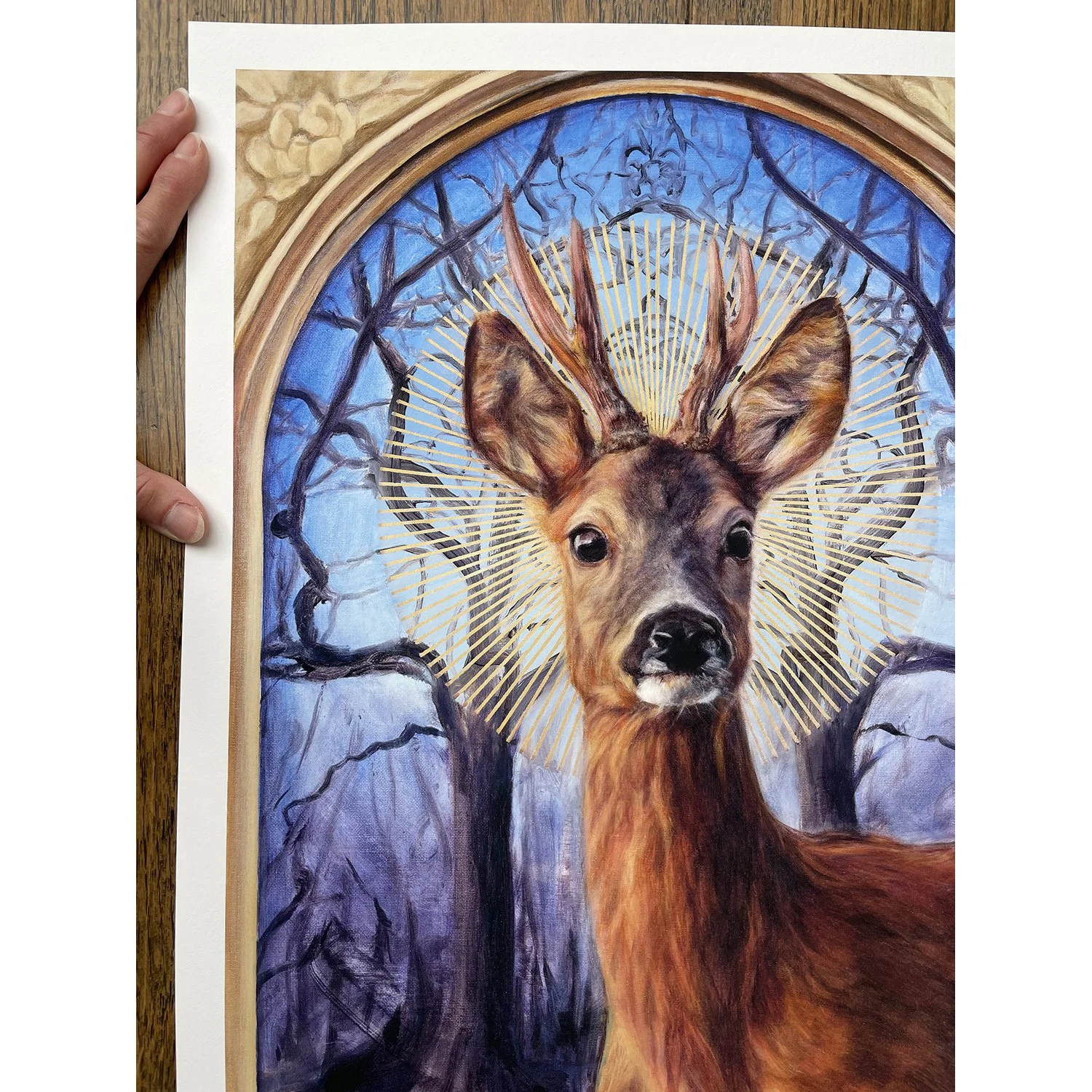 A giclee print of a roe deer buck with a sunburst halo against a background of mirrored winter trees. Available to buy. By imaginative realism artist Karina Tarin.