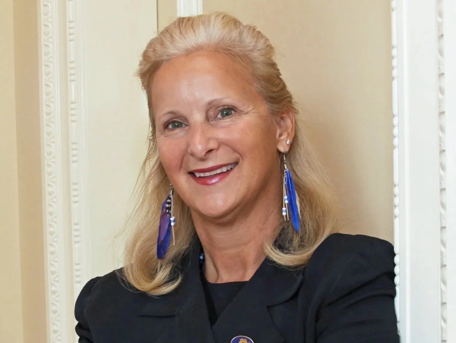 A smiling woman with shoulder-length blonde hair at a formal event.