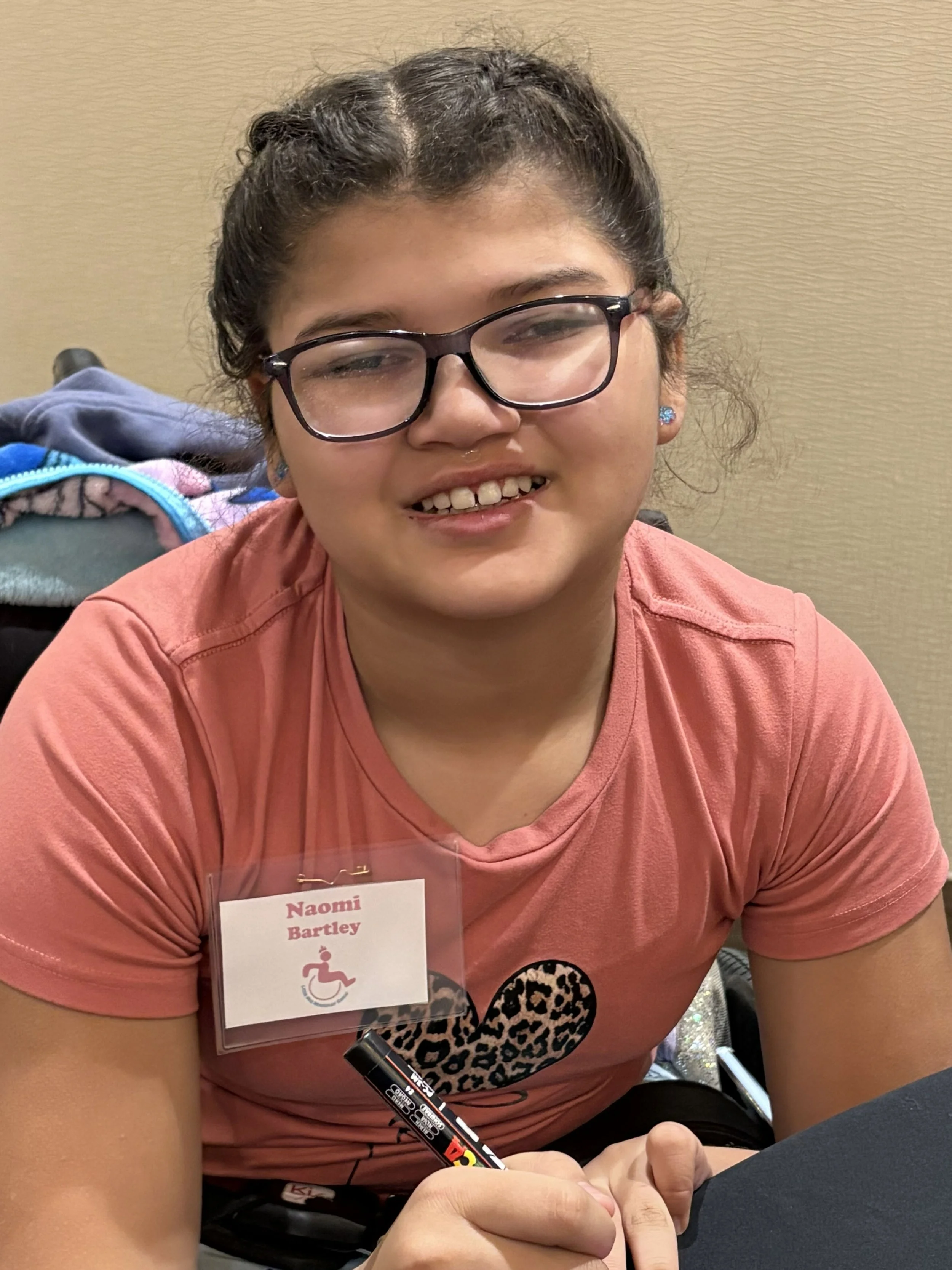 Naomi smiling for the camera as she writes on her star during a MWKS activity.
