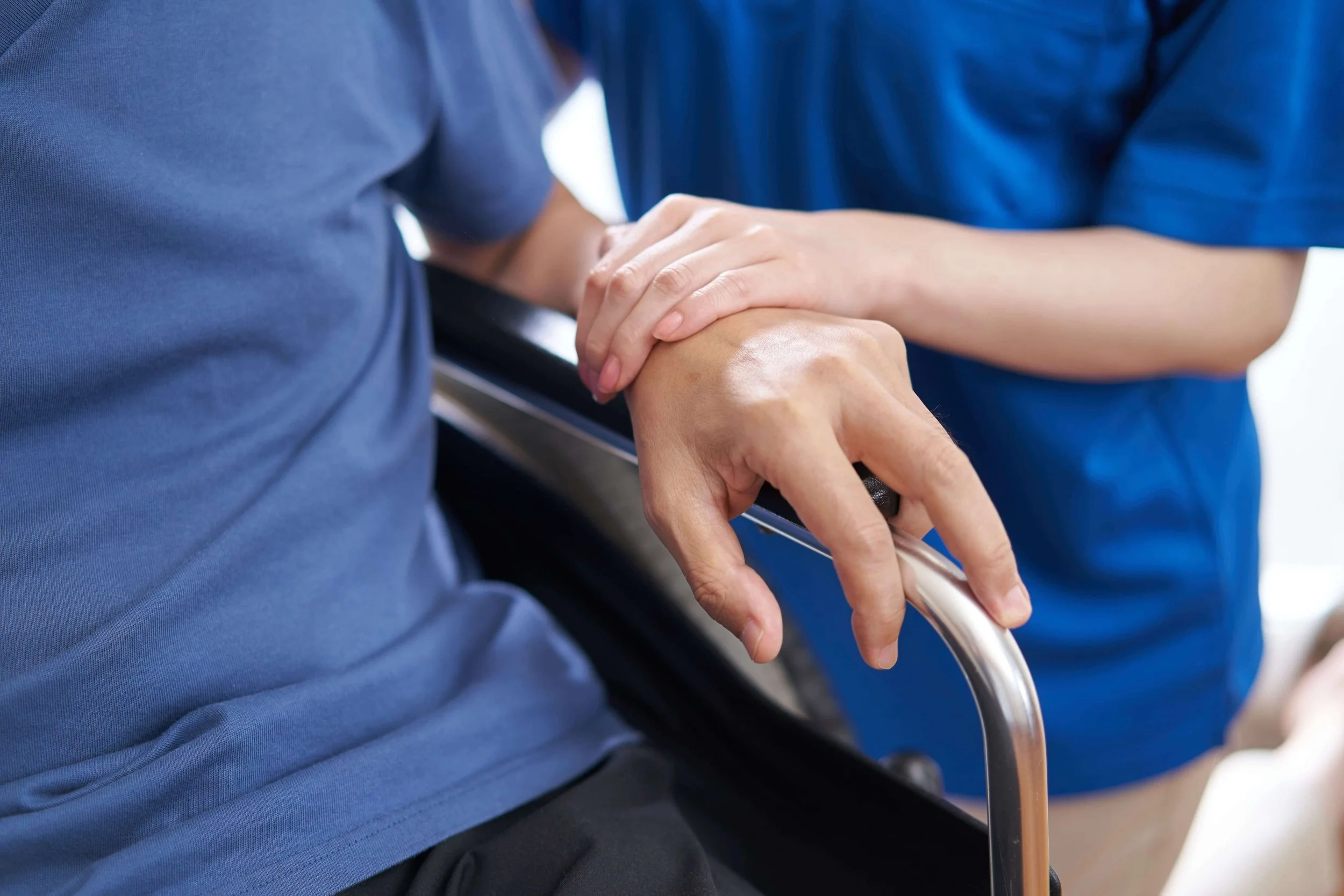 Caretaker holding the arm of a person in a wheelchair
