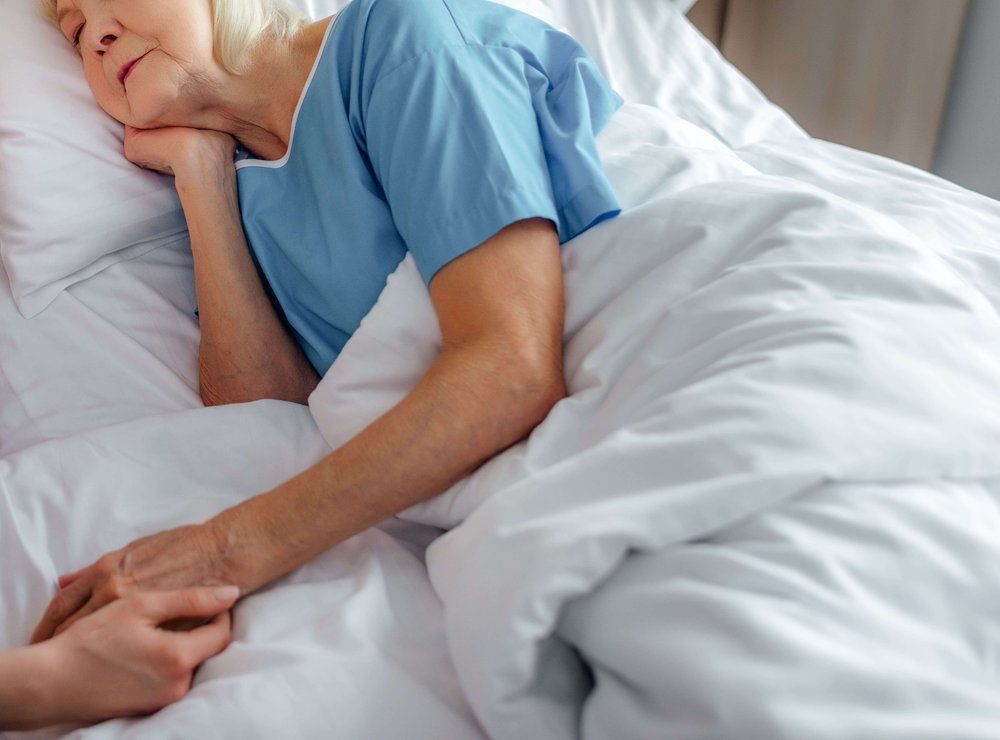 Elderly woman being repositioned in bed