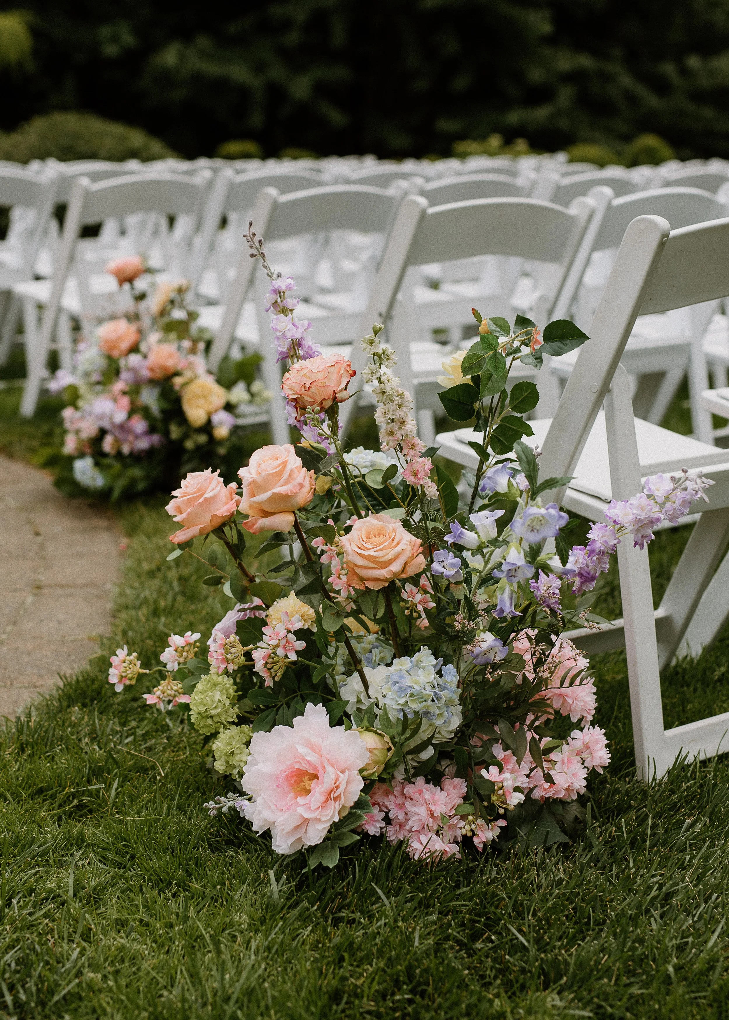 Pastel garden-style silk wedding aisle flowers with roses and greenery