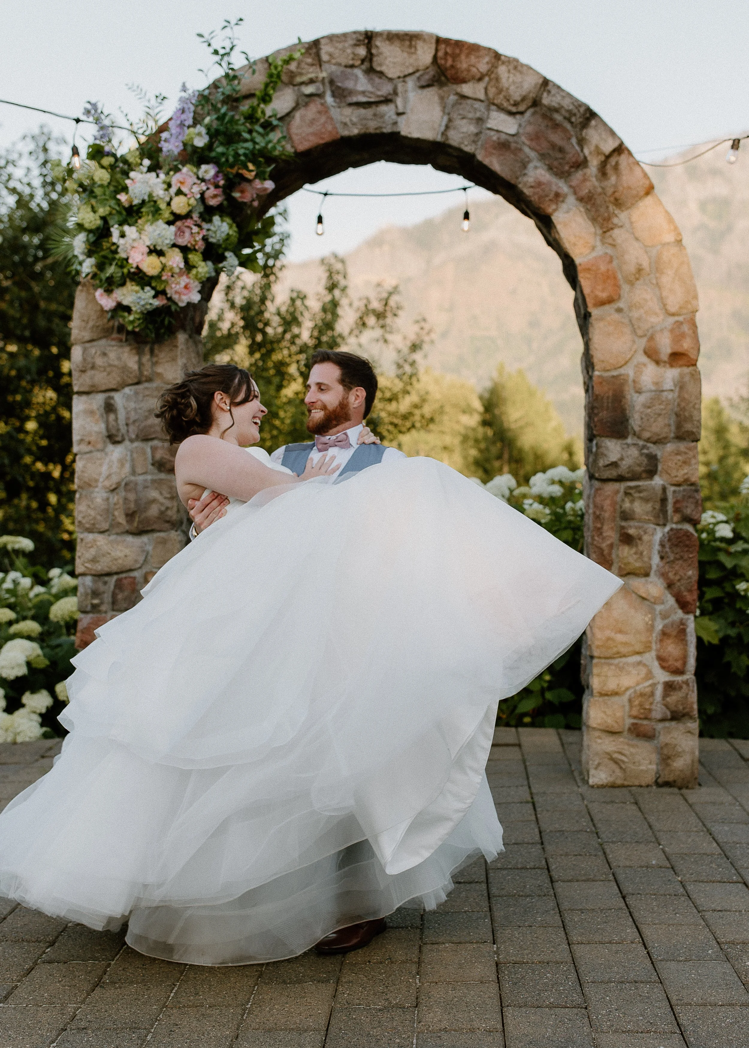 Bride and groom celebrating beneath garden-style silk wedding flower swag