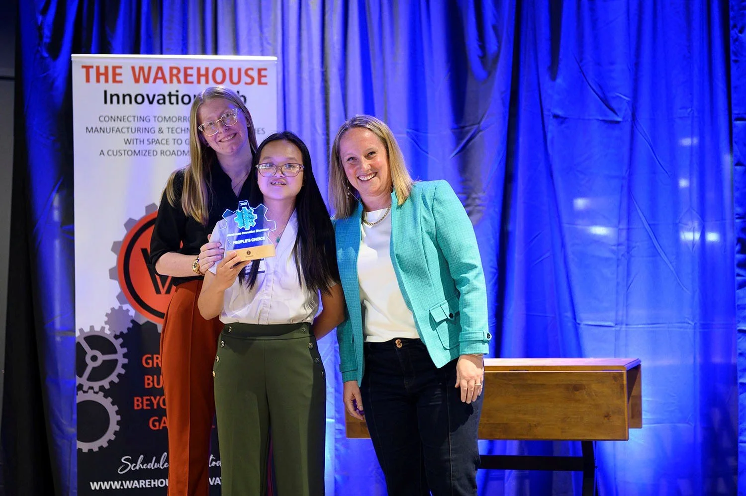 Katrina Hellmann, Elisabeth Van and Allison Seabeck posing with 2026 People's Choice Award at Innovation Showcase
