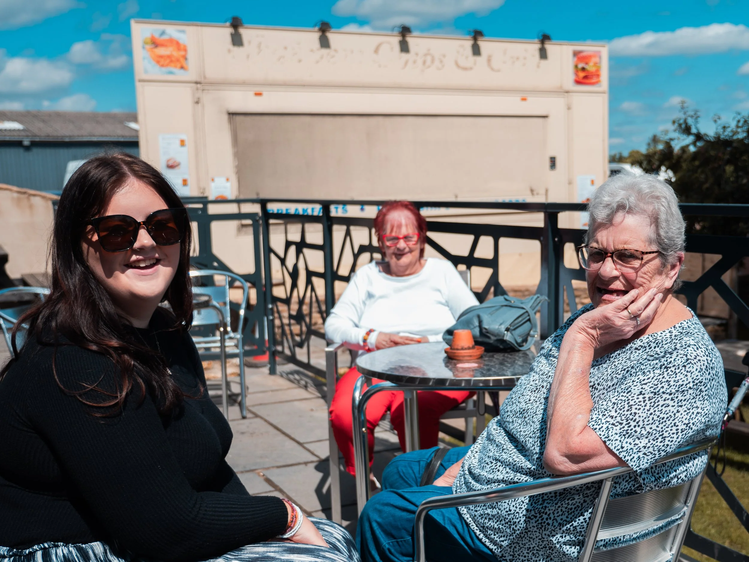 Three women chatting outside cafe