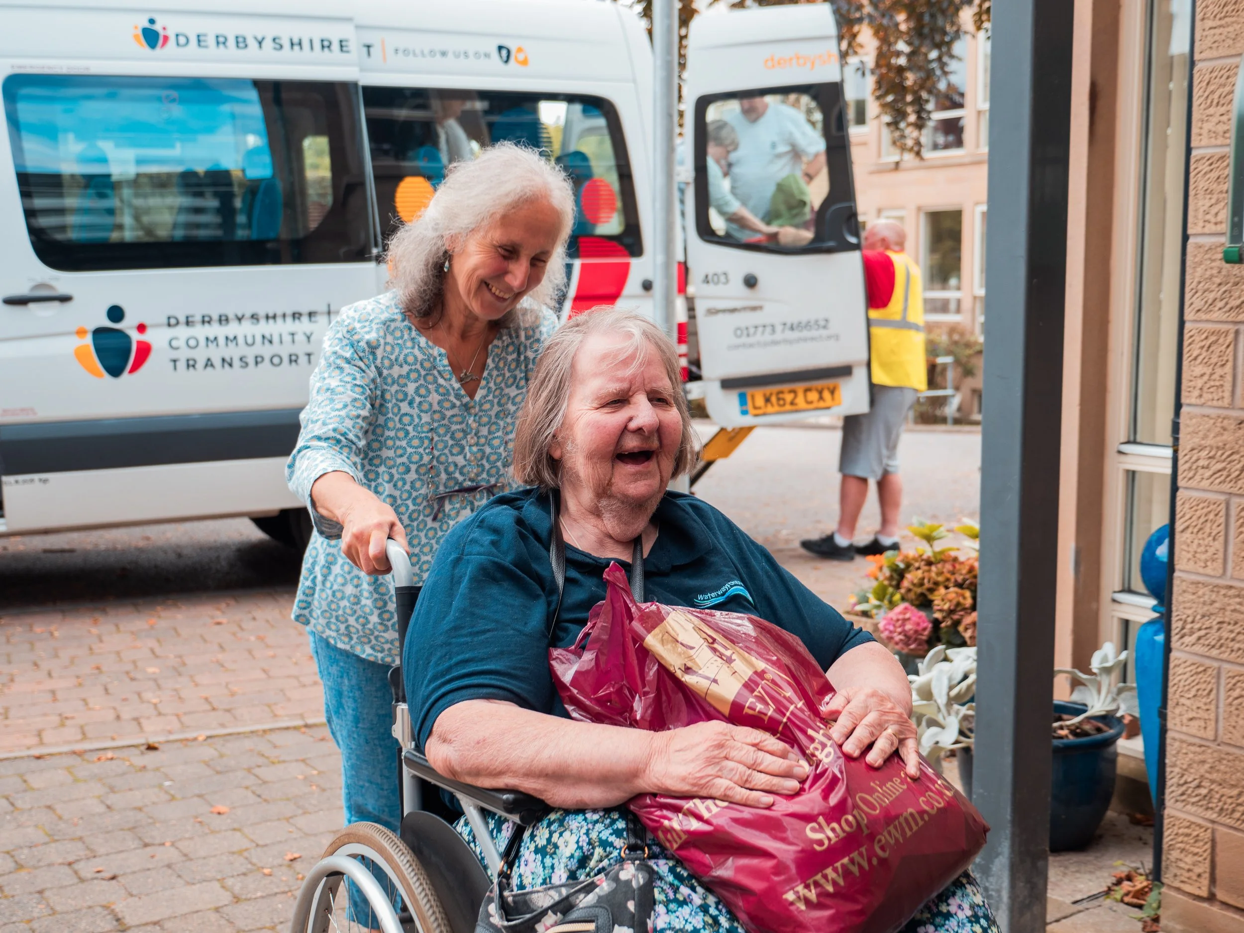 Woman in wheelchair being pushed into home