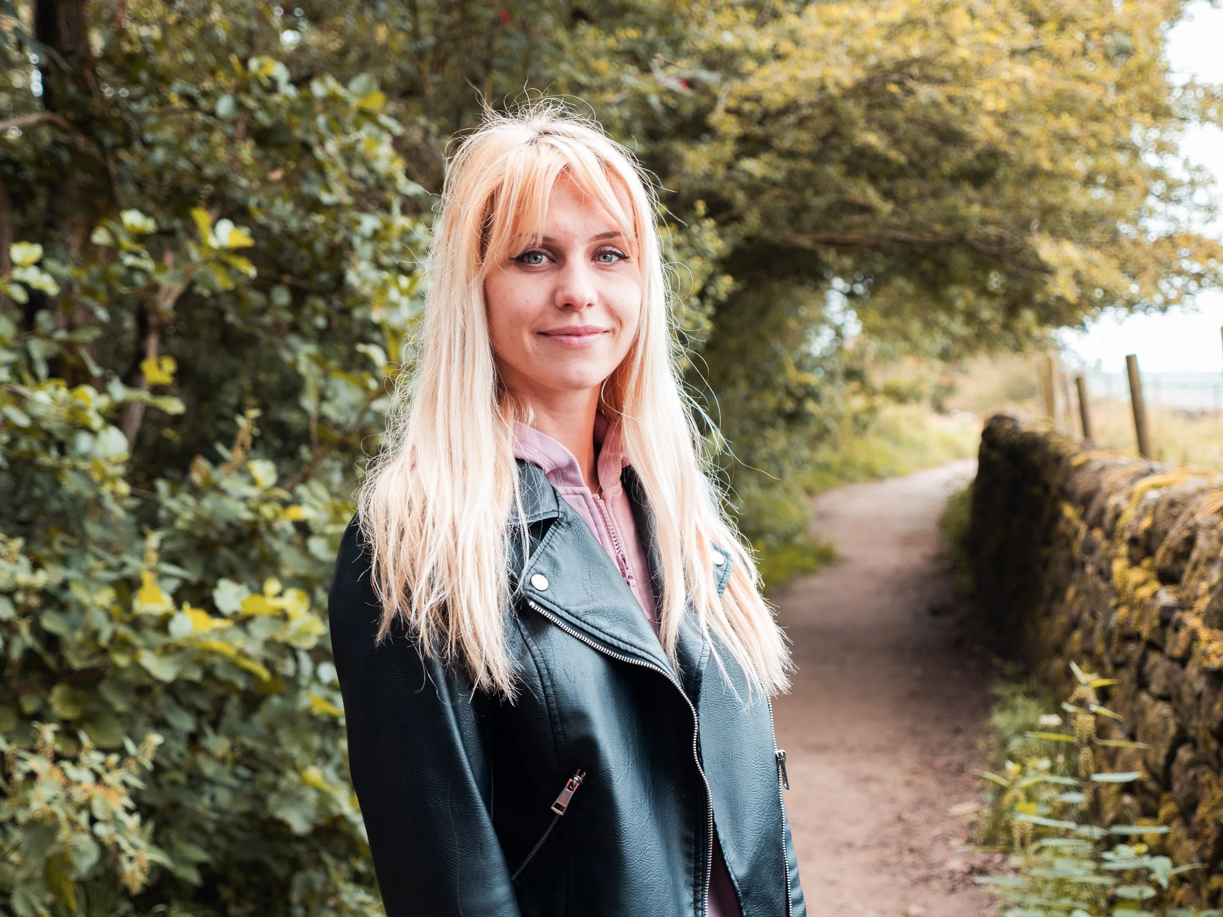 Woman with long blonde hair standing on country path