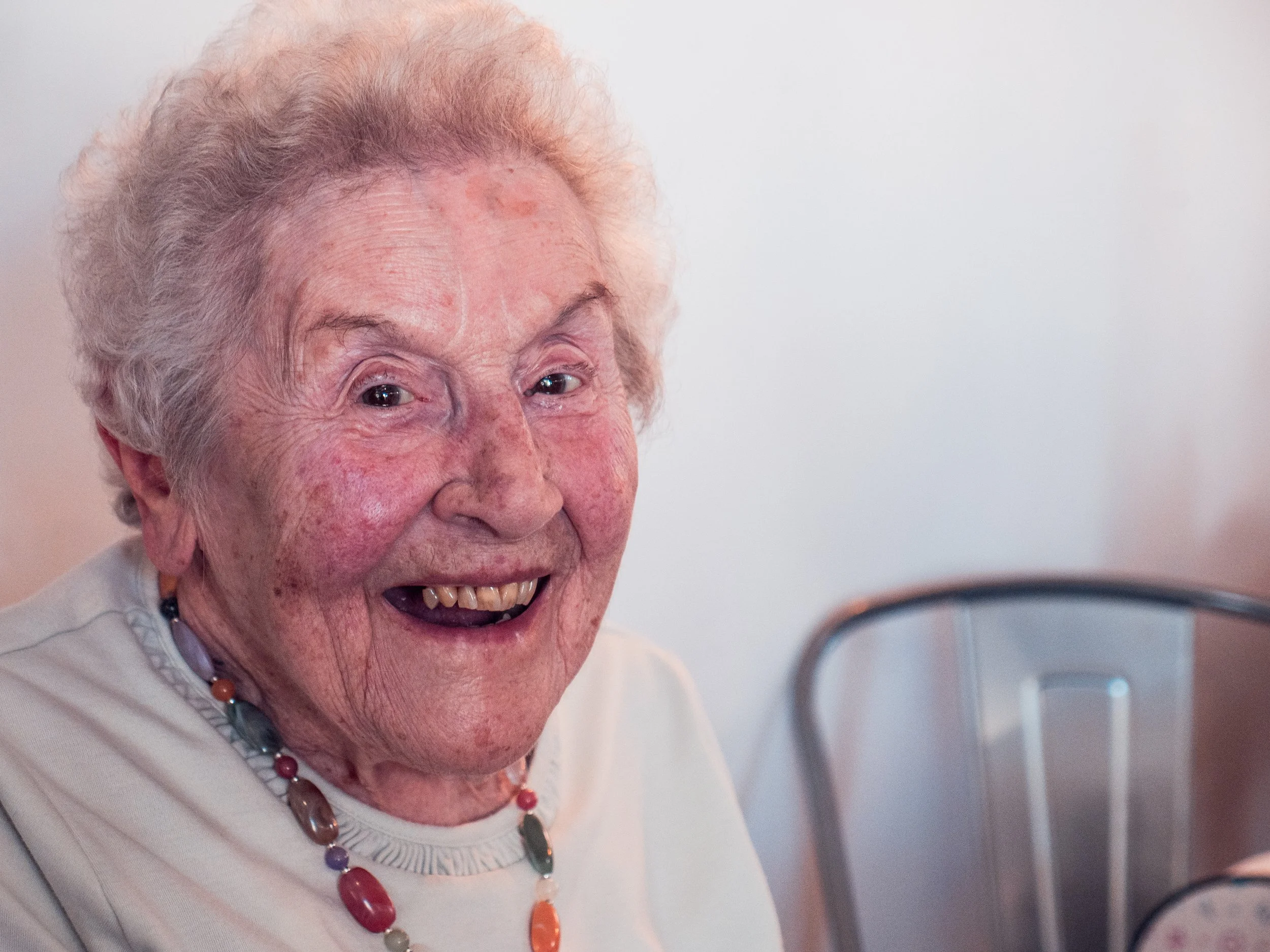 Older woman wearing beads and smiling