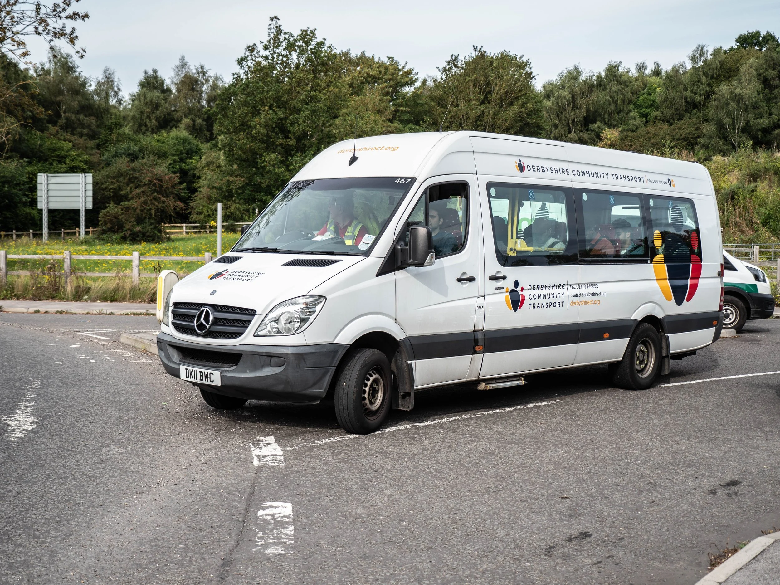 White Mercedes-Benz minibus with Derbyshire Community Transport logo and branding parked in a parking lot.