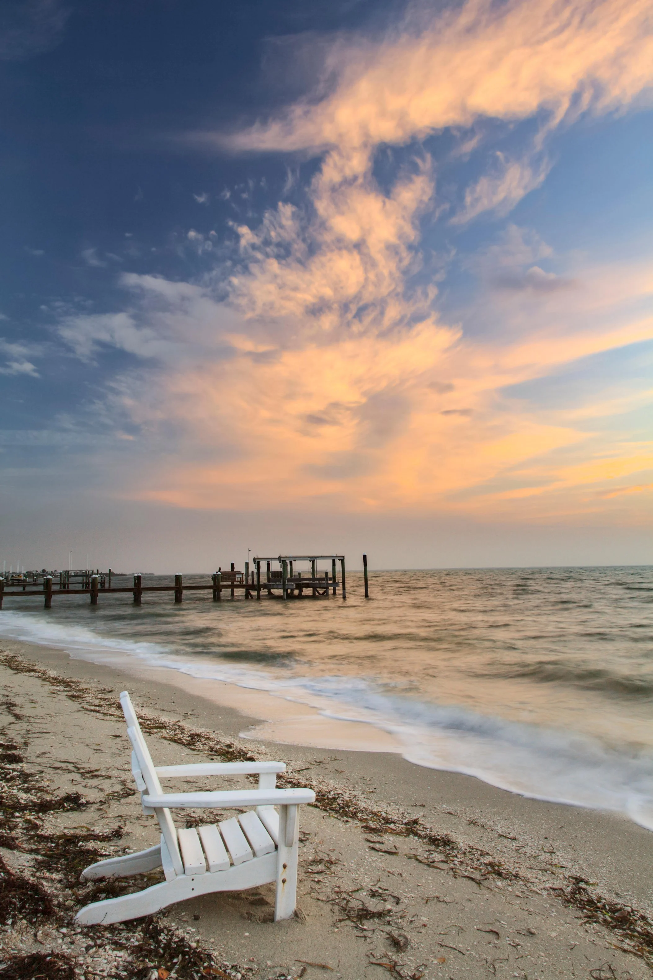 photo of wooden chair on a sandy Florida beach at sunset