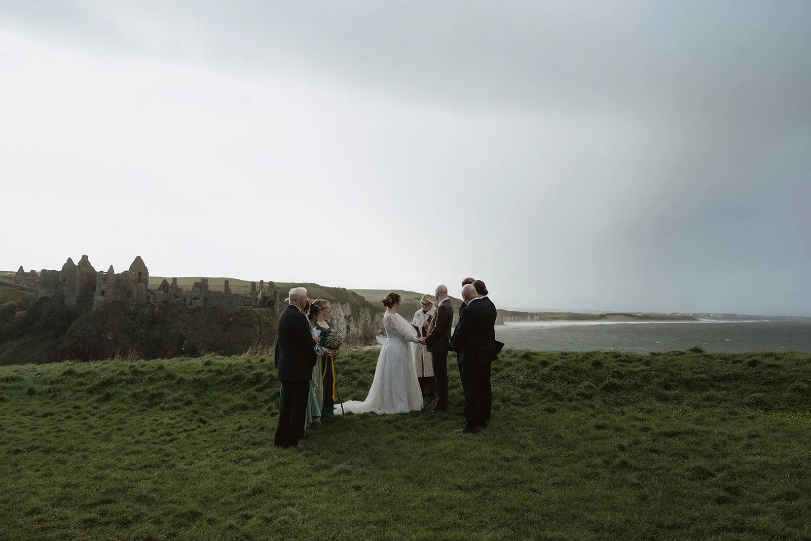 A bride and groom get married with a few of their friends and family in front of Dunluce Castle in Northern Ireland.