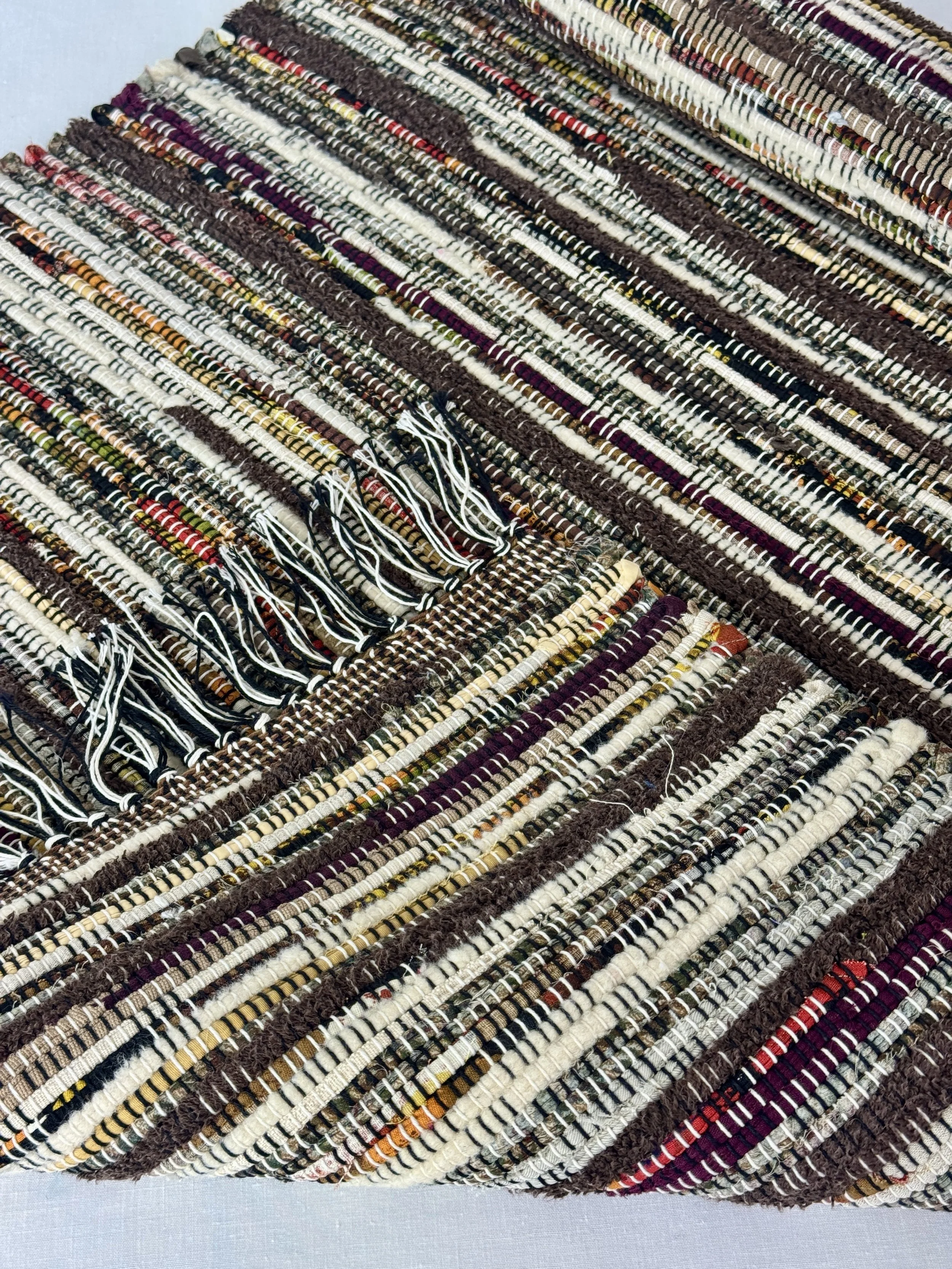 Folded handwoven rag rug showing reverse side and fringe