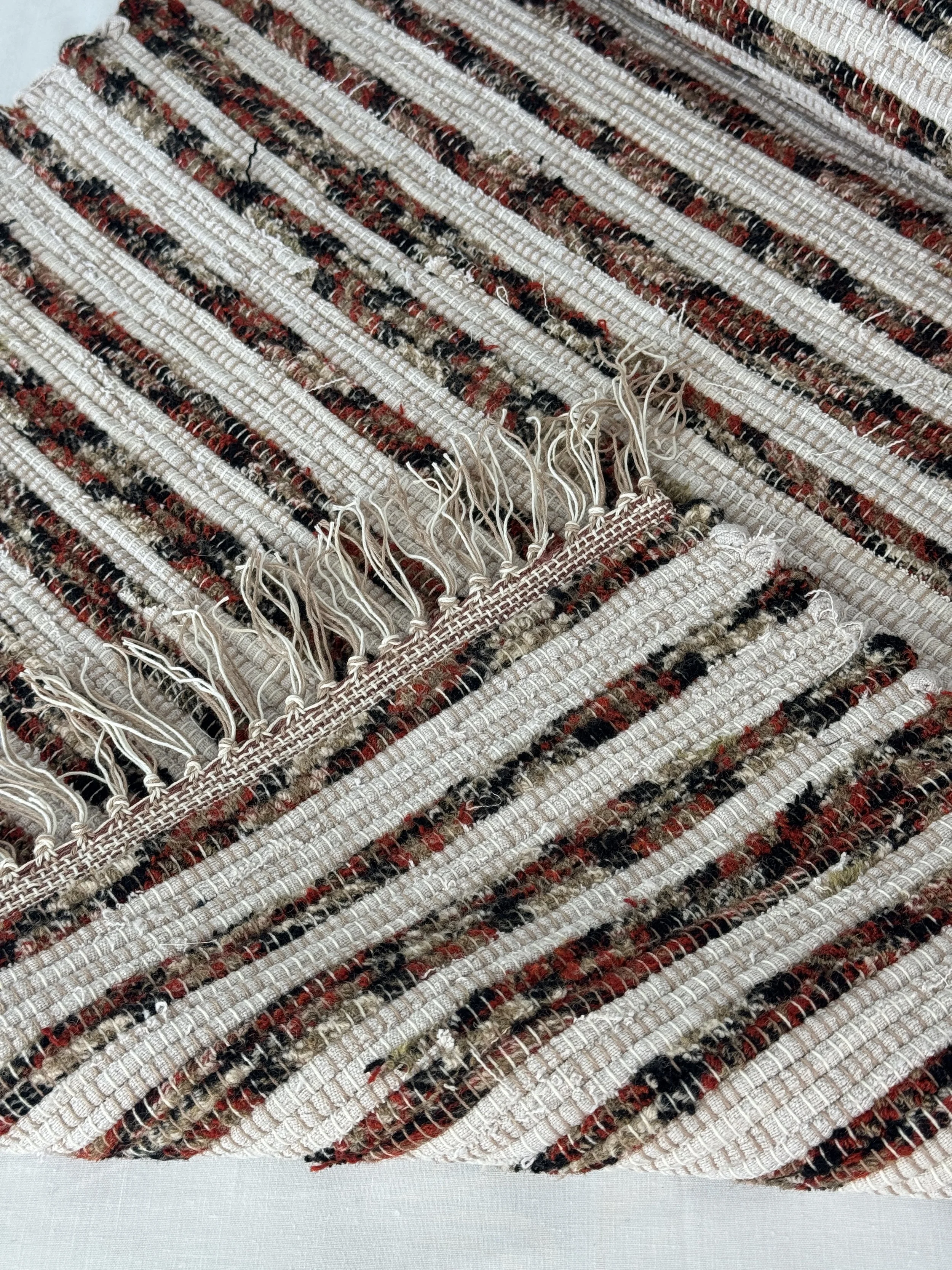 Folded handwoven rag rug showing reverse side and fringe