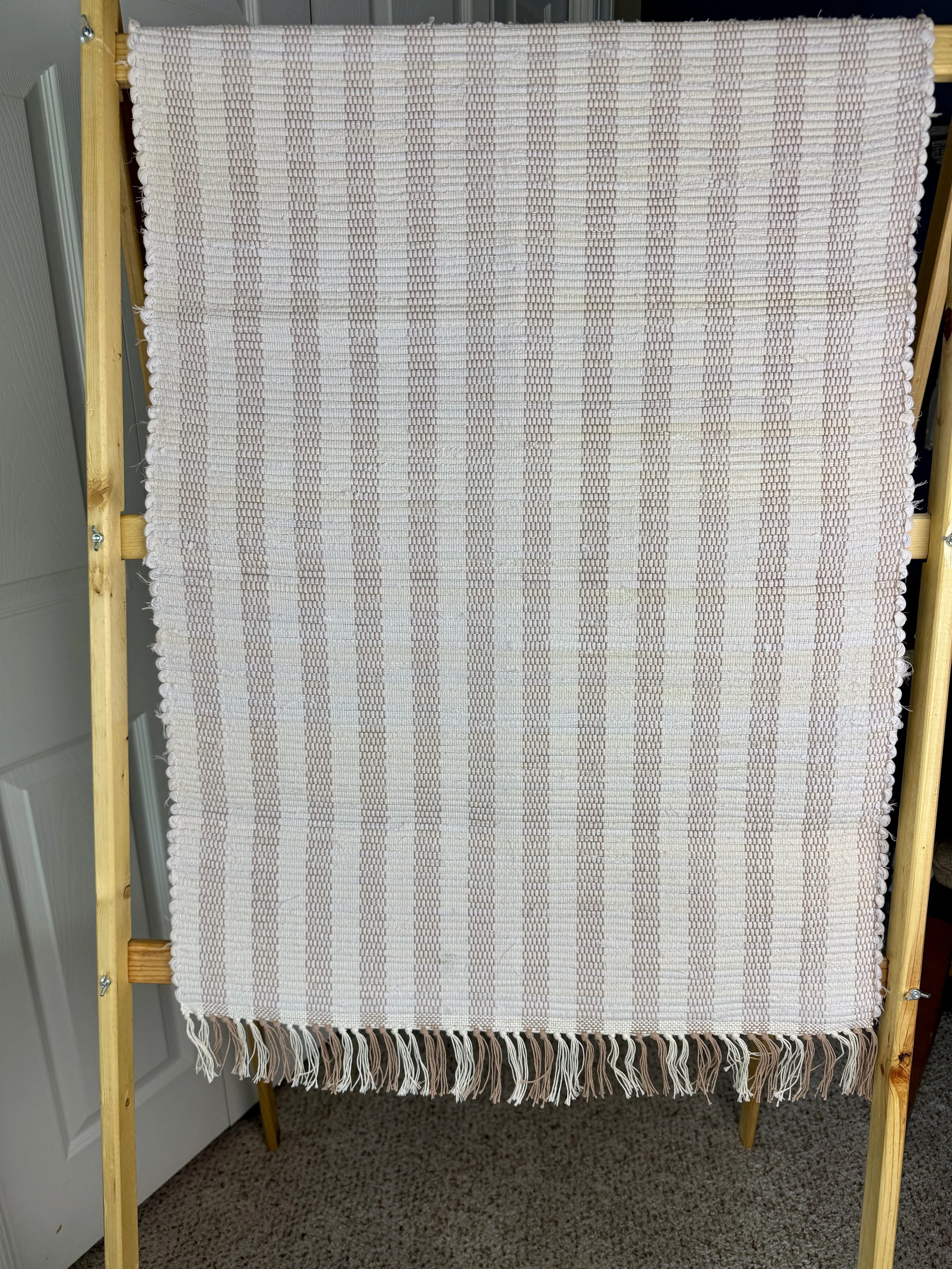 Hanging handmade recycled cotton  rag rug showing pattern and fringe