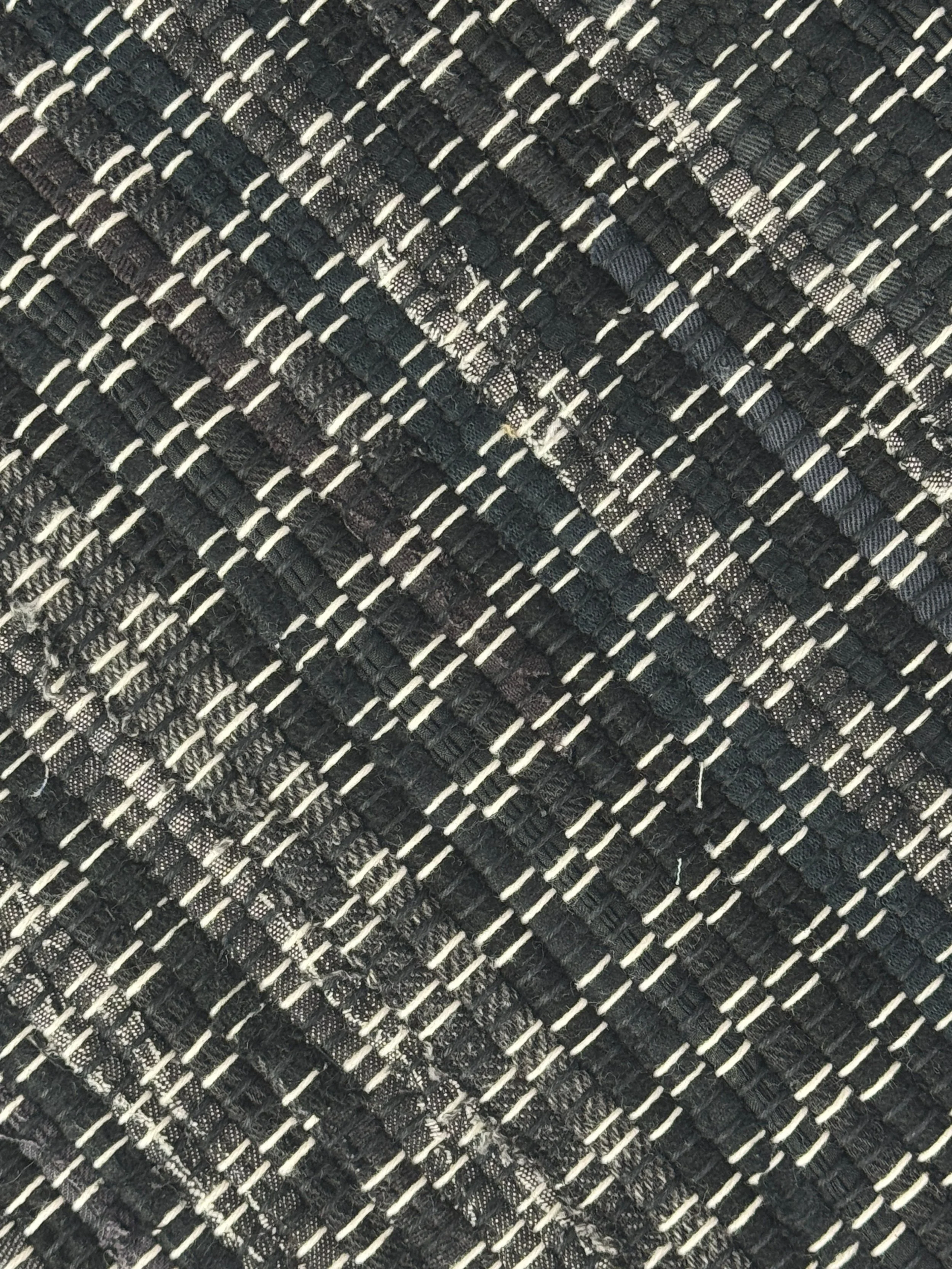 Black handwoven rag rug folded to show fringe and reversible woven cotton blend texture.