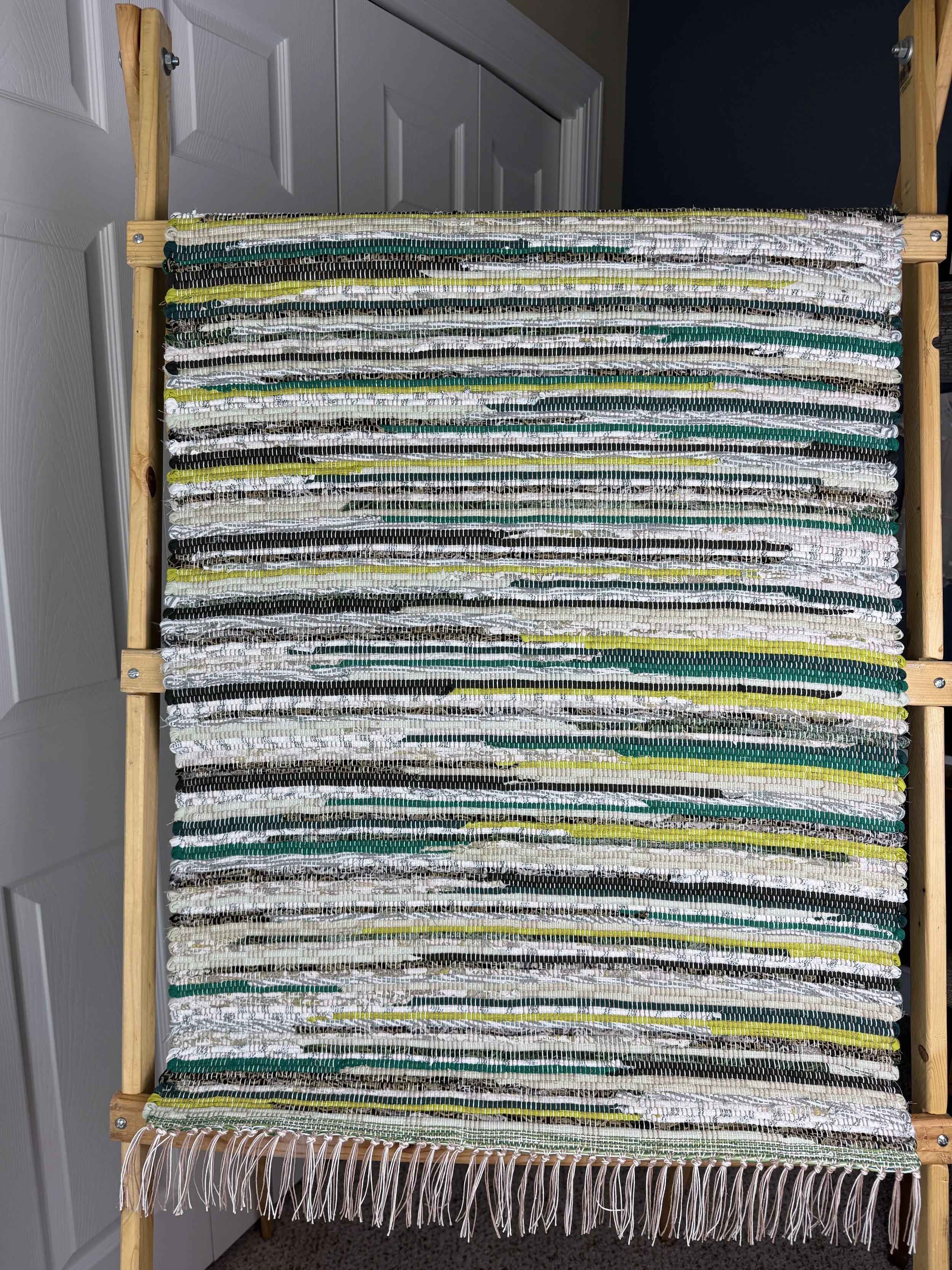 Handwoven green rag rug hung showing pattern