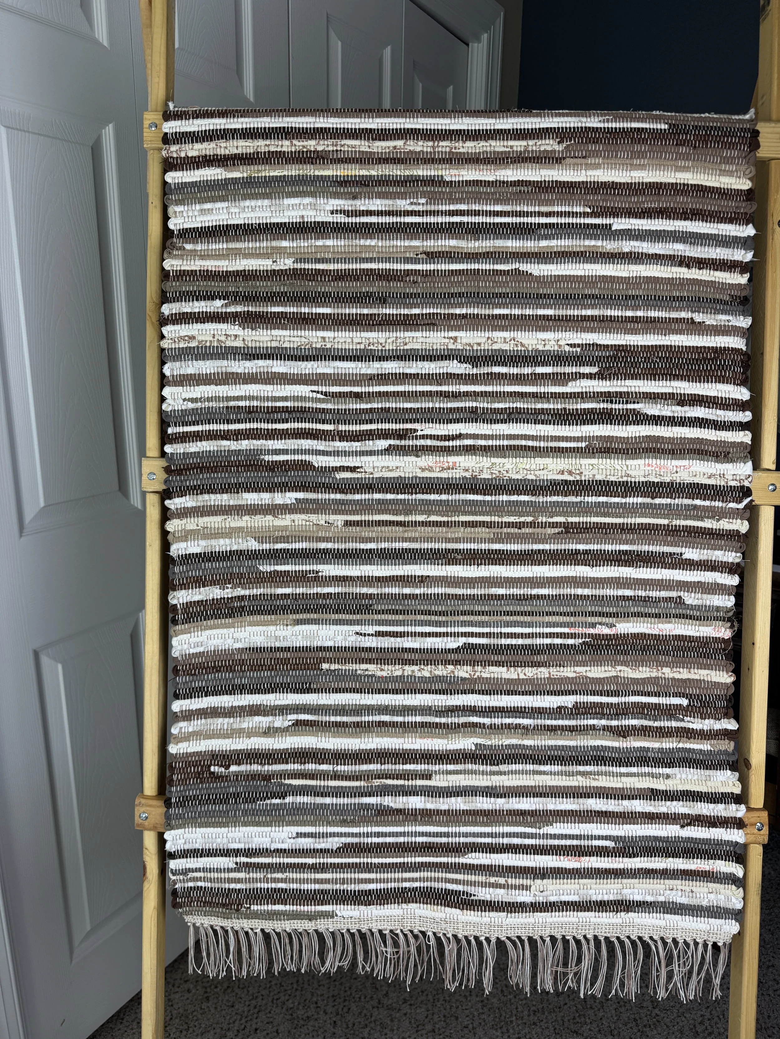 Hanging handmade recycled cotton rag rug showing pattern and fringe