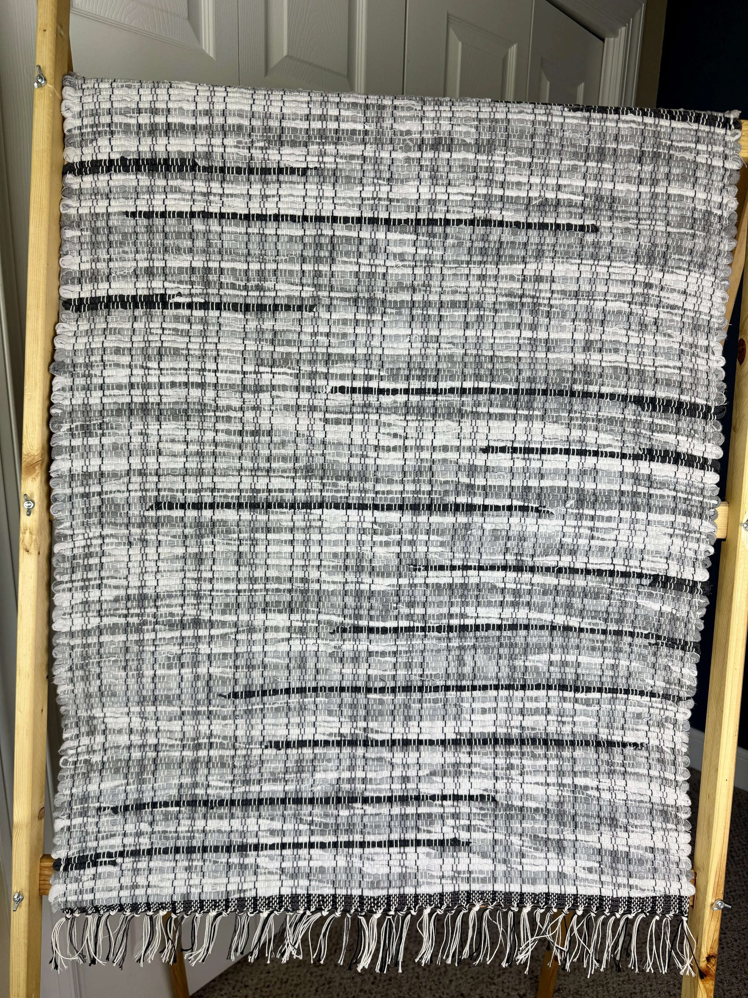 Hanging handmade recycled cotton blend rag rug showing pattern and fringe